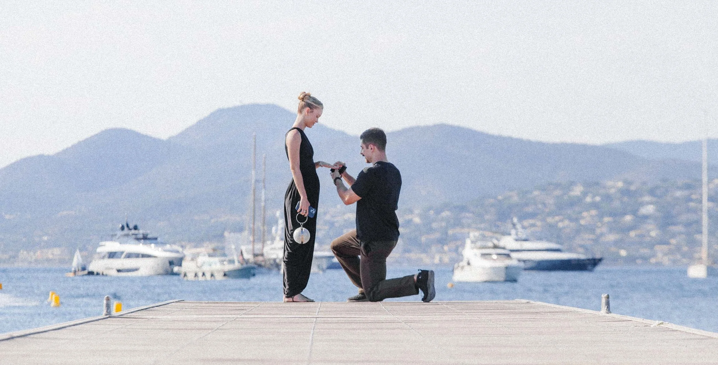 Demande en mariage sur un ponton du Golfe de Saint-Tropez, yachts au mouillage et collines des Maures en arrière-plan