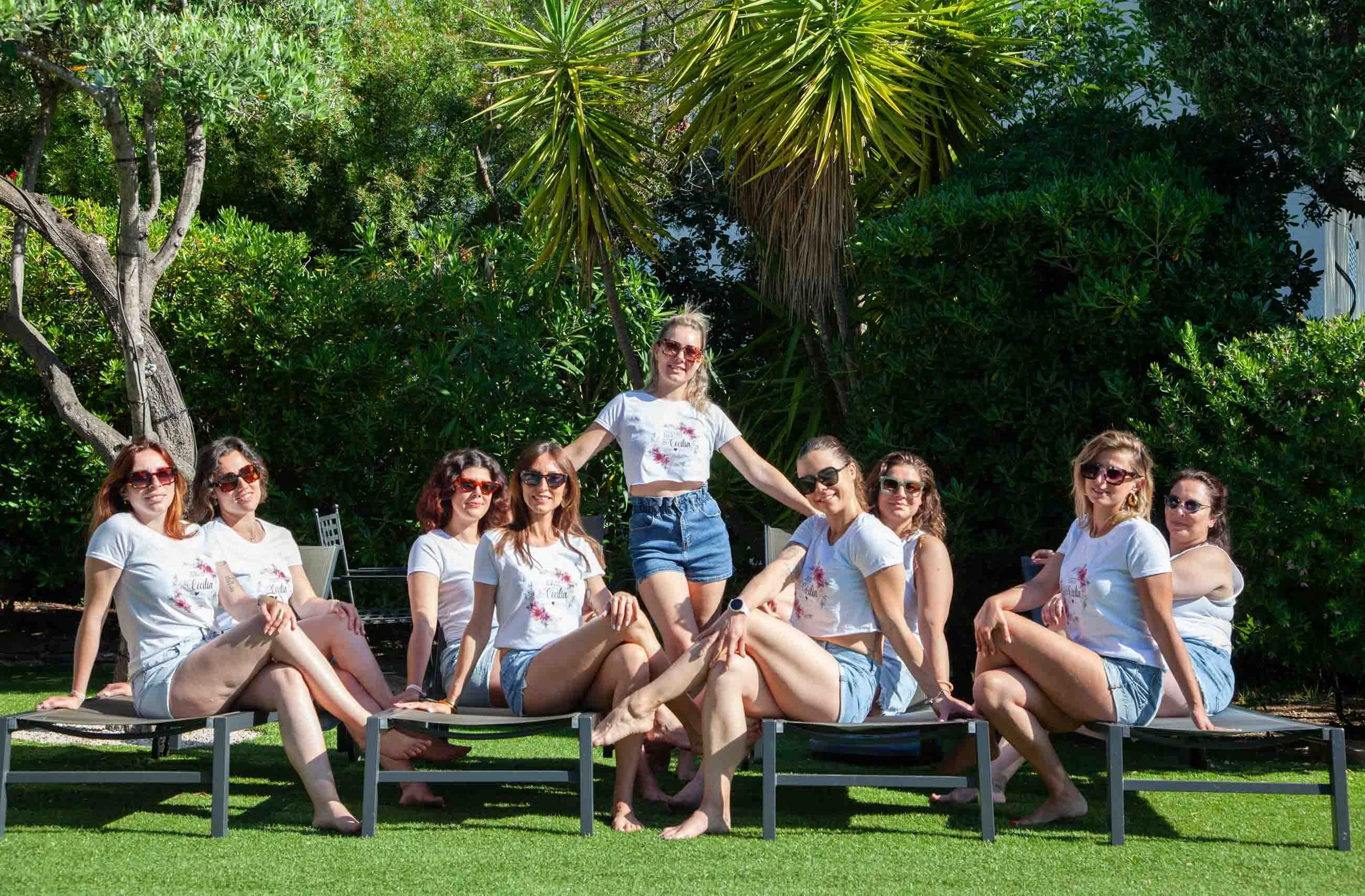 Group of friends in matching t-shirts and sunglasses in a villa garden during a bachelorette photo shoot in the Gulf of Saint-Tropez