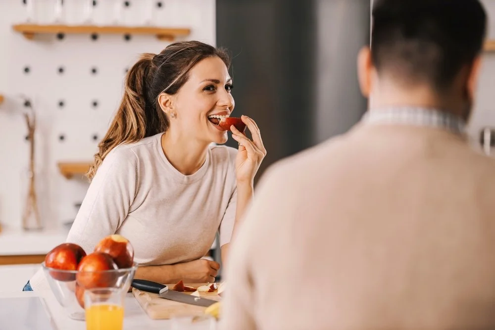 smiling woman eating a slice of an apple