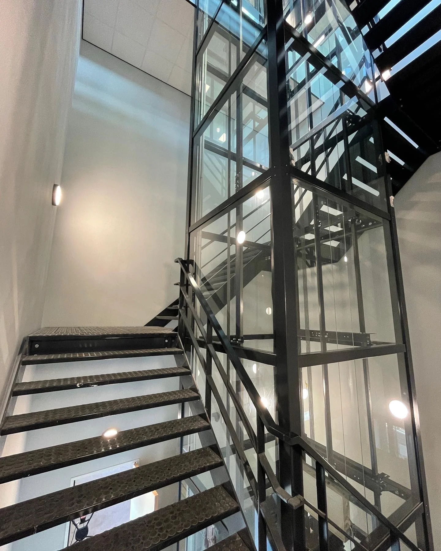 Interieur van een modern gebouw met een open trappenhuis, een metalen Trap en glazen liften.