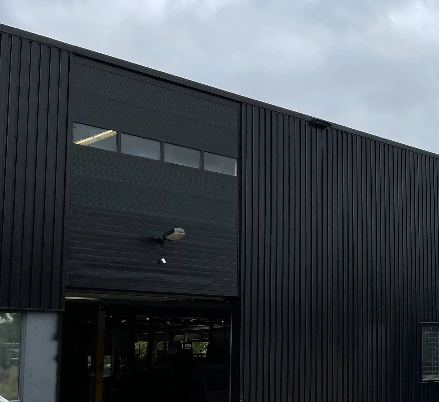 Moderne zwarte gebouw met verticale panelen en een hoog raam bij de bovenkant