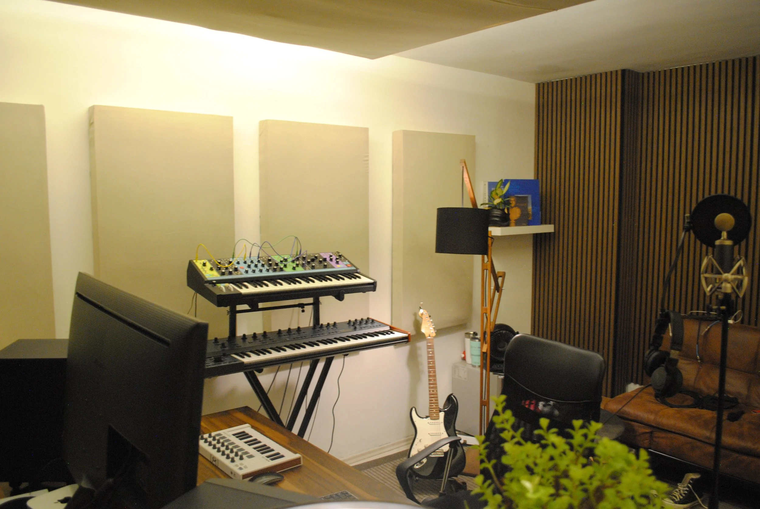 Estudio de grabación con teclado, guitarra eléctrica, micrófono, auriculares y equipo de sonido.