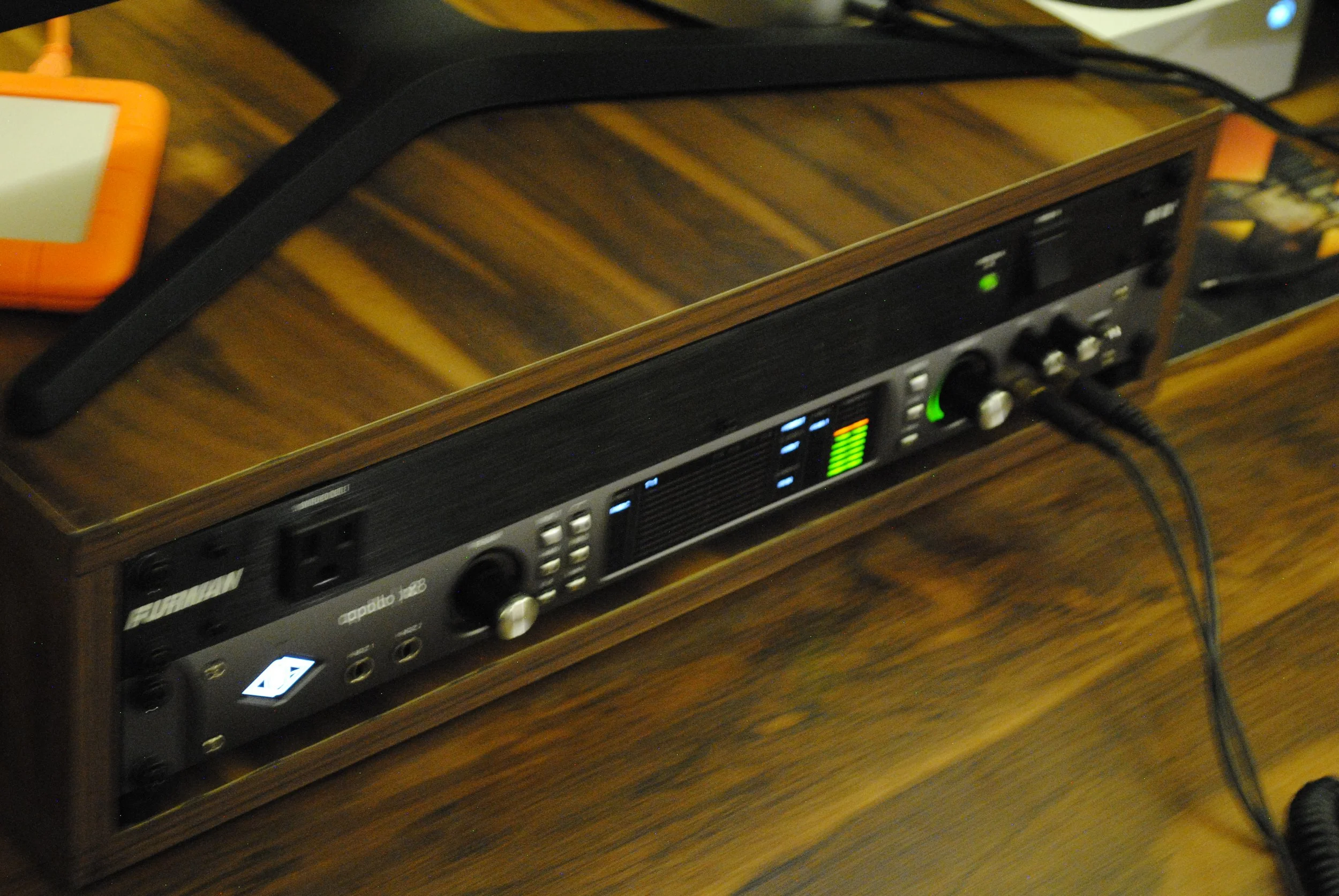 Unidad de efectos de sonido conectada a una mesa de mezclas en madera sobre una mesa de madera.