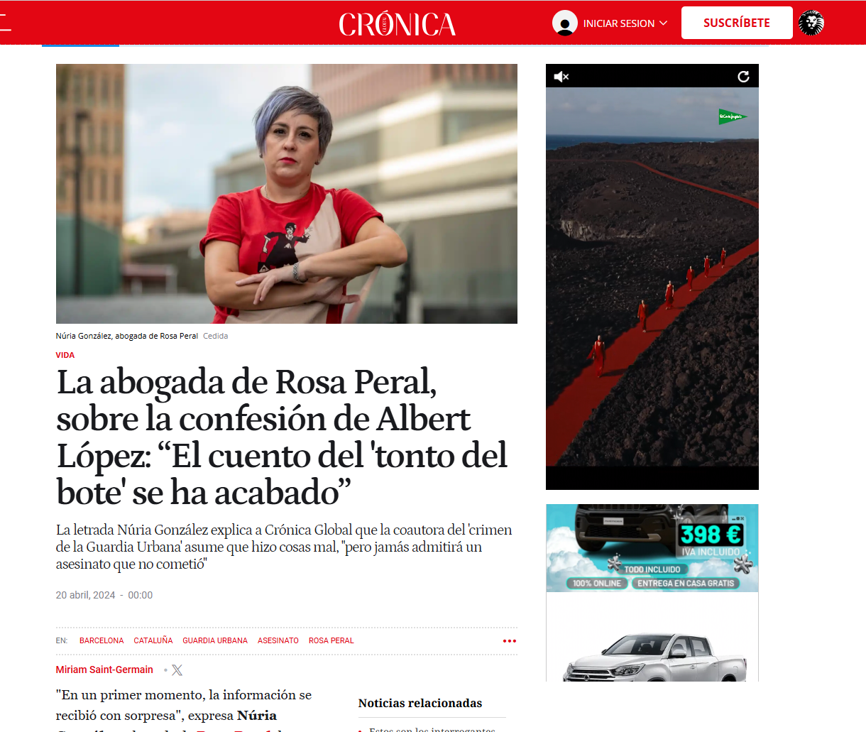 Mujer con cabello gris y morado en el cabello, con camiseta rojo y beige, con los brazos cruzados, en un entorno urbano.