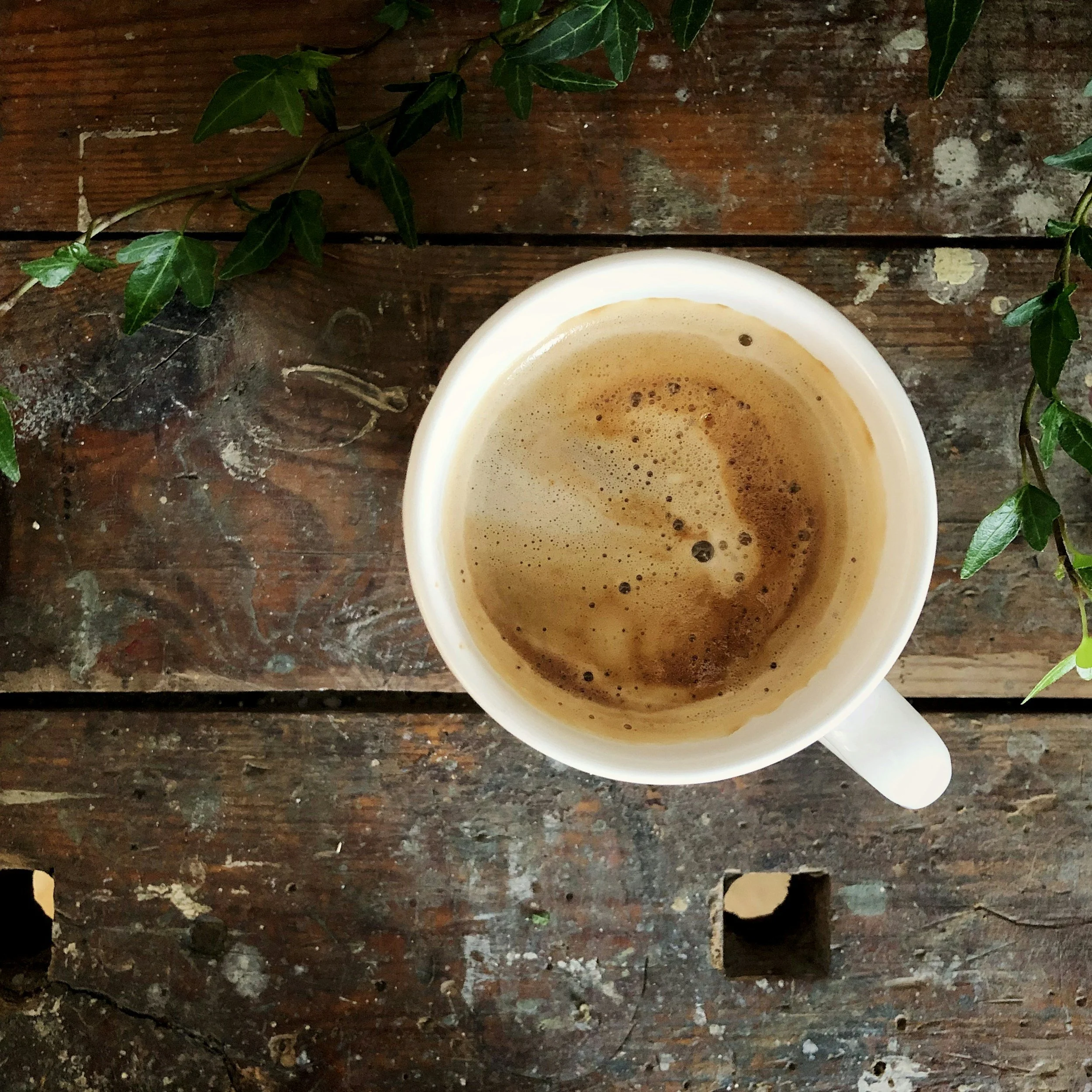 Interior of an empty barn with wooden beams and walls, with sunlight coming through a square opening in the roof.