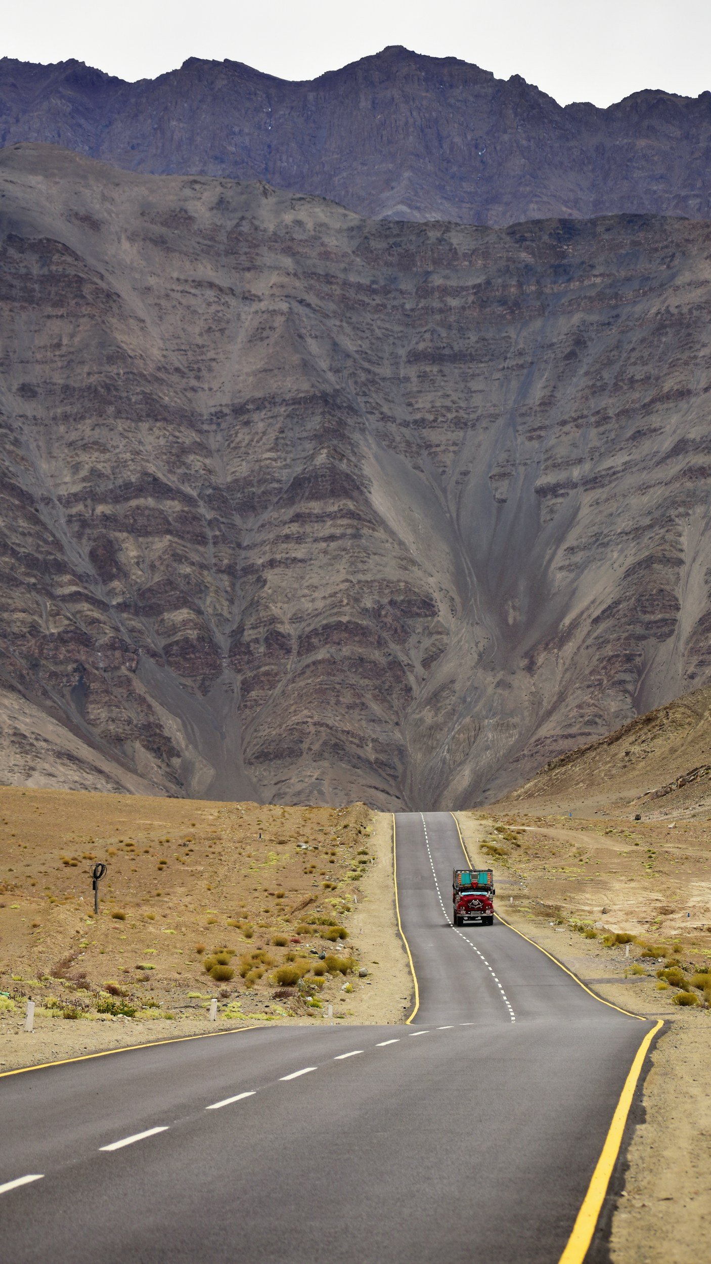 A winding open highway through a desert landscape with mountains in the background.