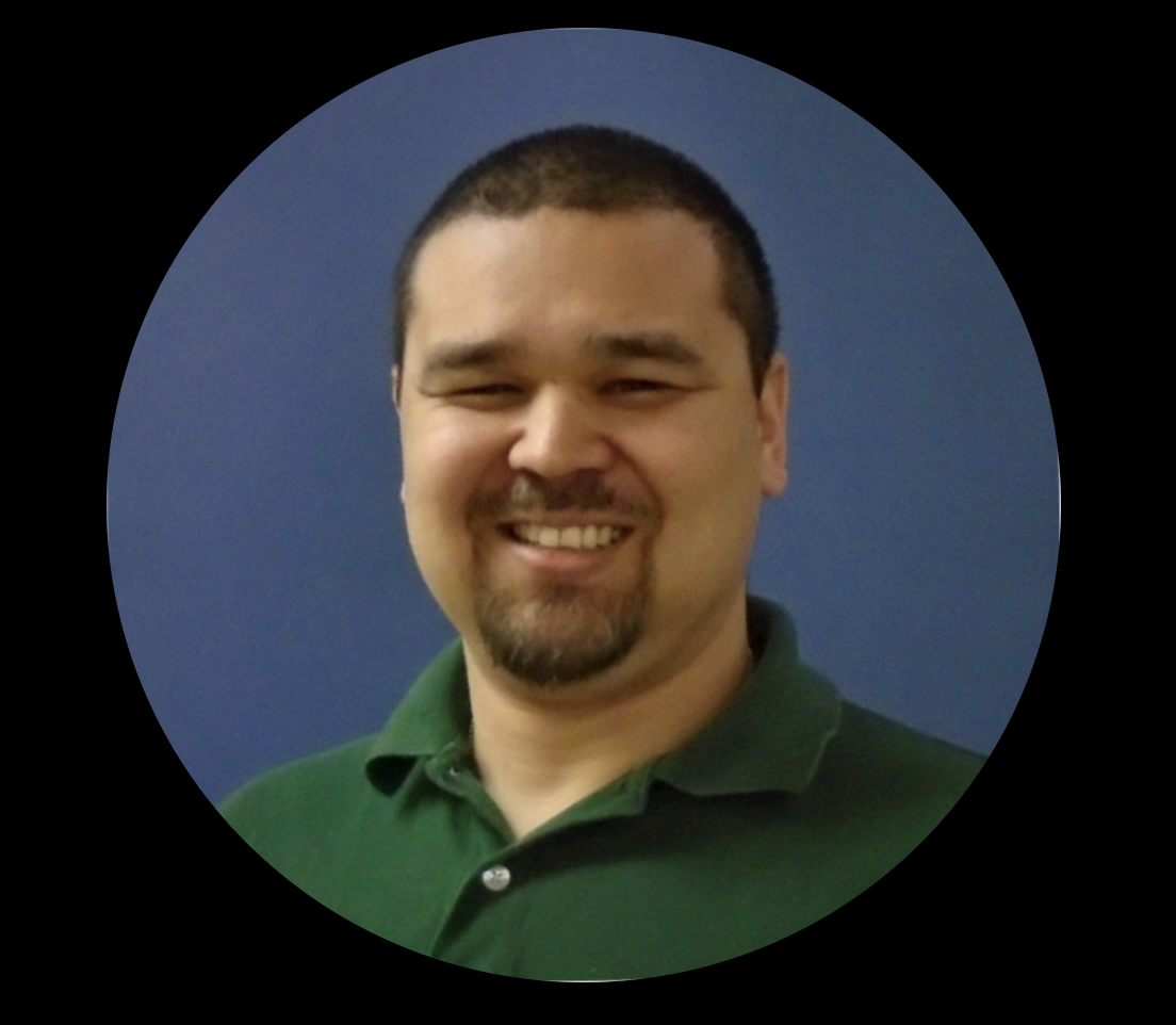 Smiling person wearing a green polo shirt against a blue background.