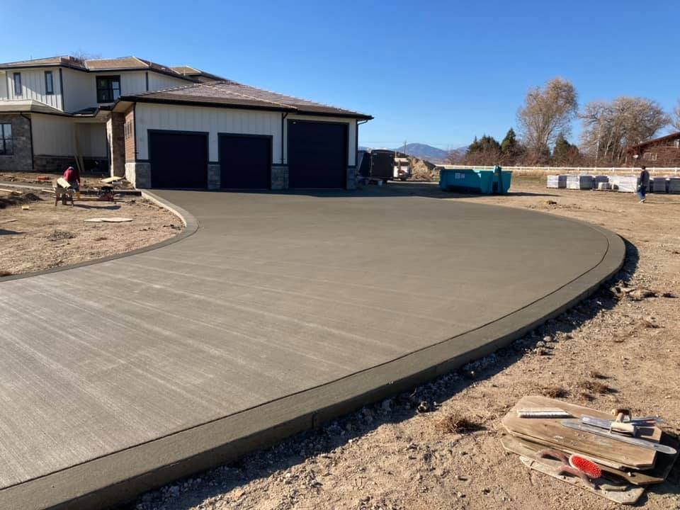 Freshly paved concrete driveway in front of a modern house with three garages.