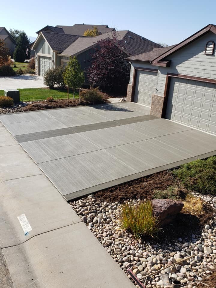 Freshly laid concrete driveway in a residential neighborhood with green lawns and landscaped areas