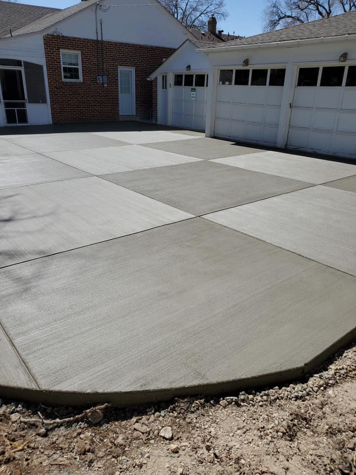 Freshly poured concrete driveway in front of a brick house and garage.