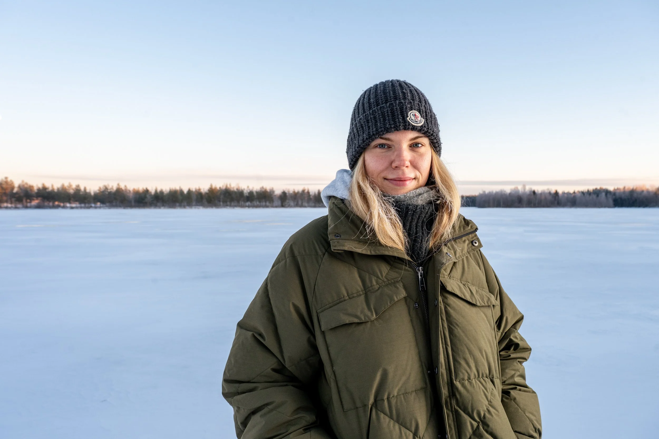 Vaaleahiuksinen nuori nainen ulkona joen jäällä poseeraa kameralle