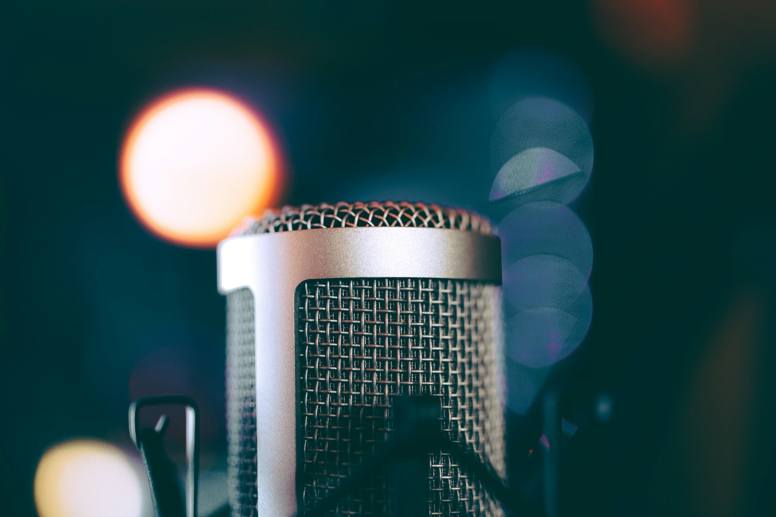 Close-up of a studio microphone with a blurred background featuring bokeh lights.