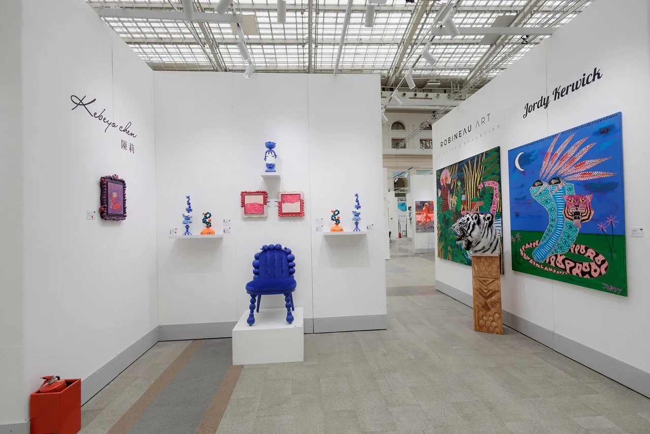 Art exhibition featuring paintings and sculptures with animal motifs, including a colorful snake and tiger portraits, displayed on white walls in a modern gallery space.