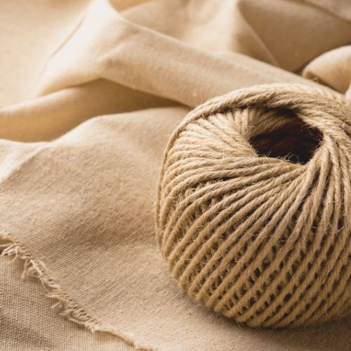 A close-up of a ball of beige twine resting on a beige fabric surface.