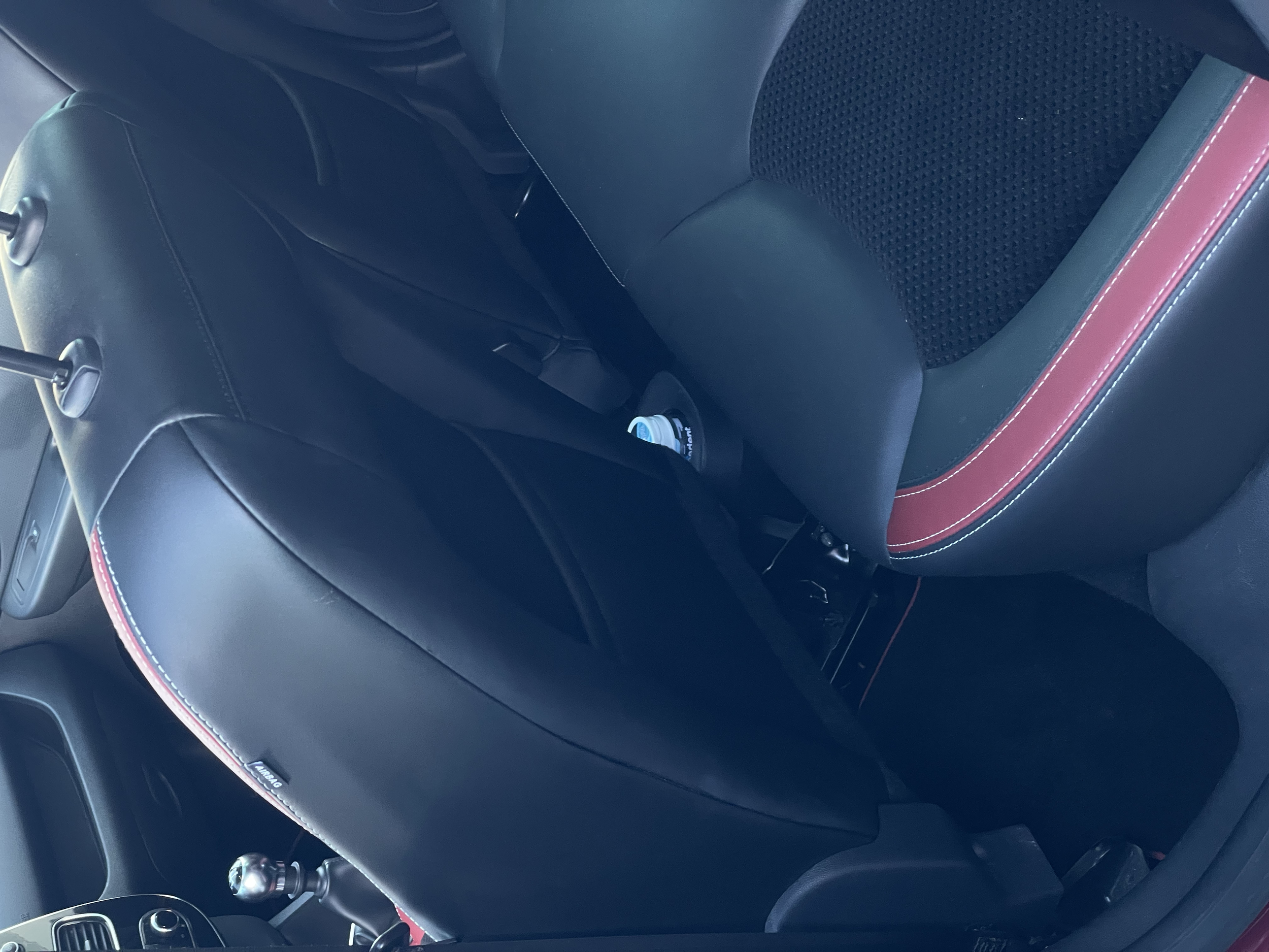 Intérieur d'une voiture avec sièges noirs et liseré rouge.