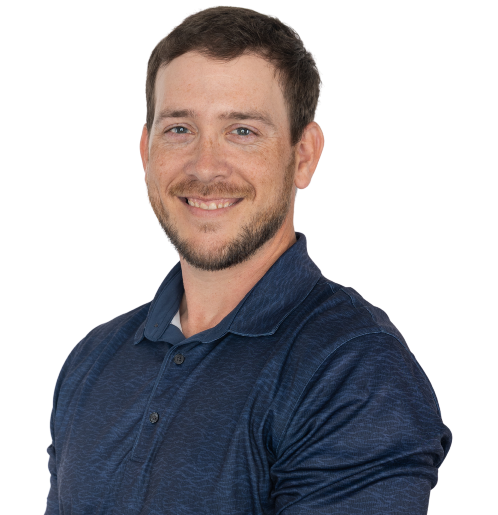 A smiling man with short brown hair, blue eyes, and a beard, wearing a navy blue button-up shirt, standing against a background with abstract purple and red lines.