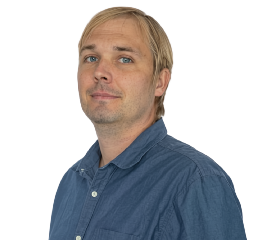 A man with blonde hair and blue eyes wearing a blue button-up shirt, looking at the camera with a slight smile.