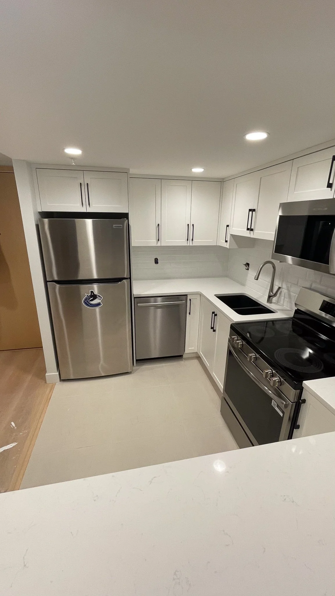 newly renovated kitchen with white cabinets and stainless steel appliances