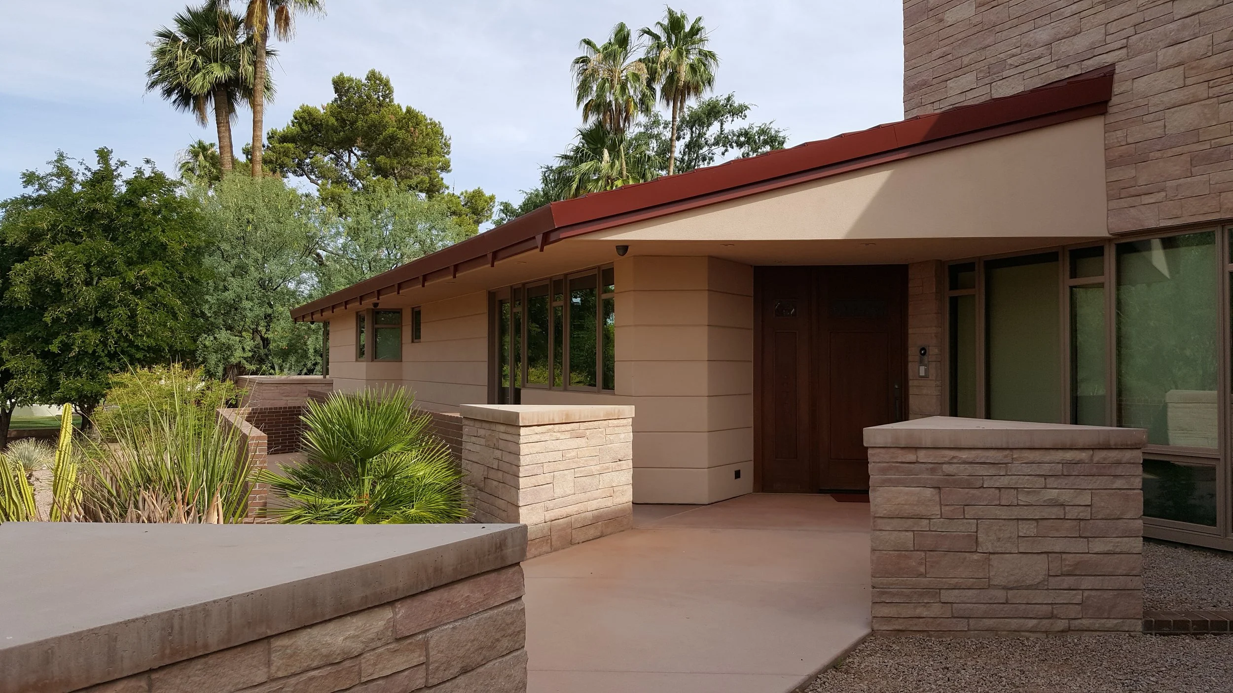 Modern house exterior with stone walls, large windows, and surrounded by greenery.