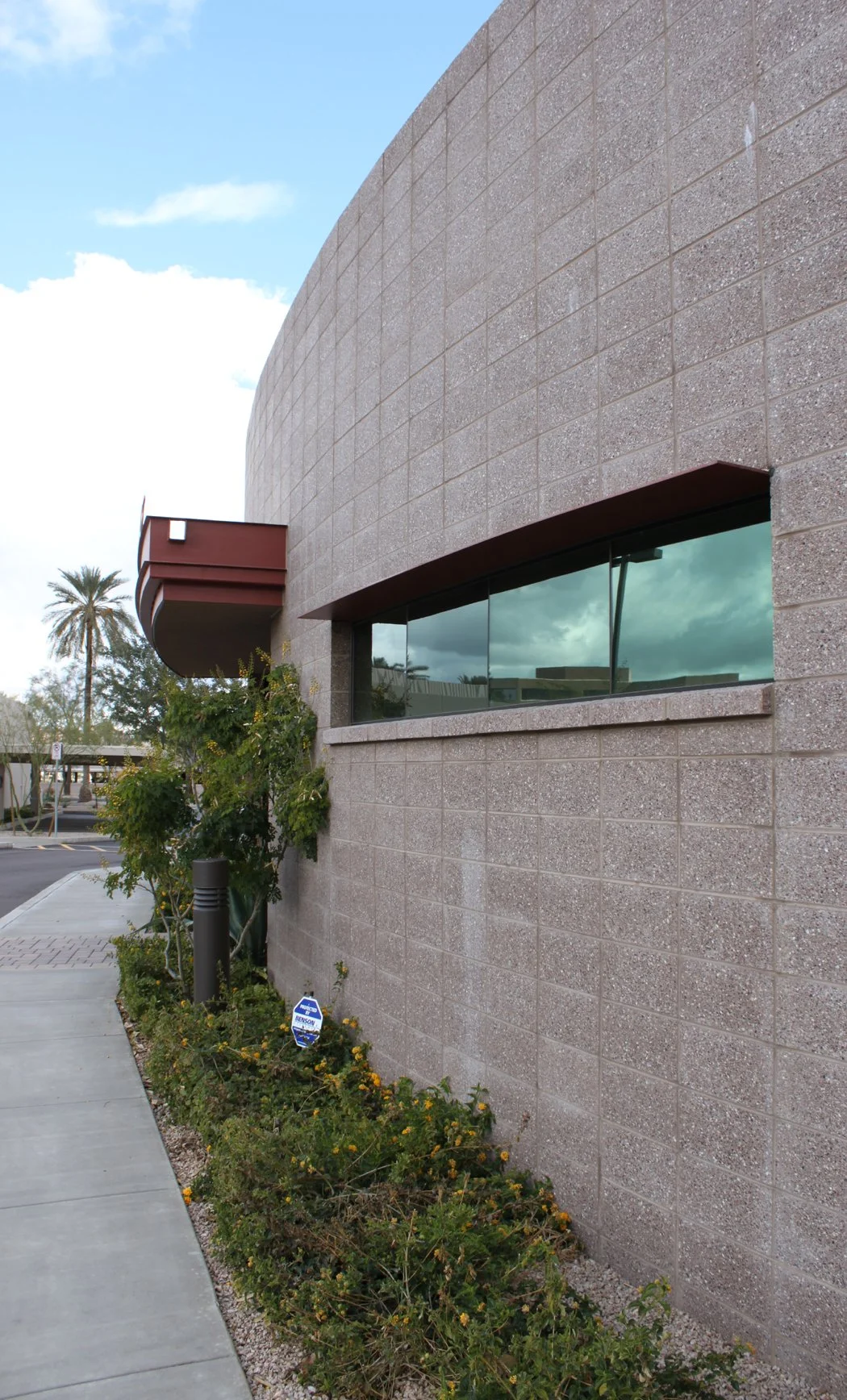 Exterior of a Colton Construction commercial building with a curved brick wall and linear window, surrounded by landscaping and a sidewalk in an urban setting.