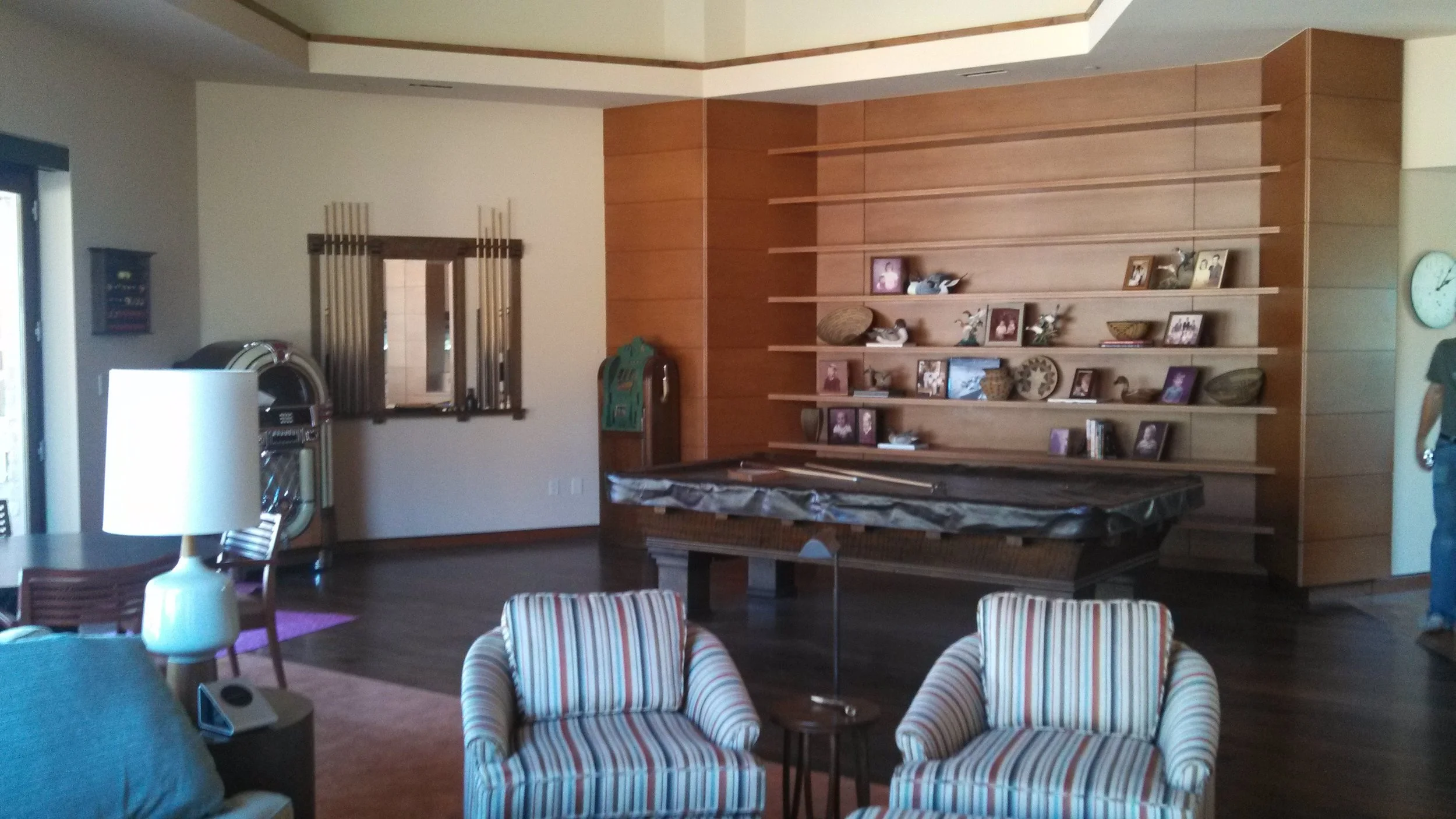 Living room with a pool table, built-in shelving, pool cues on the wall, and a jukebox.