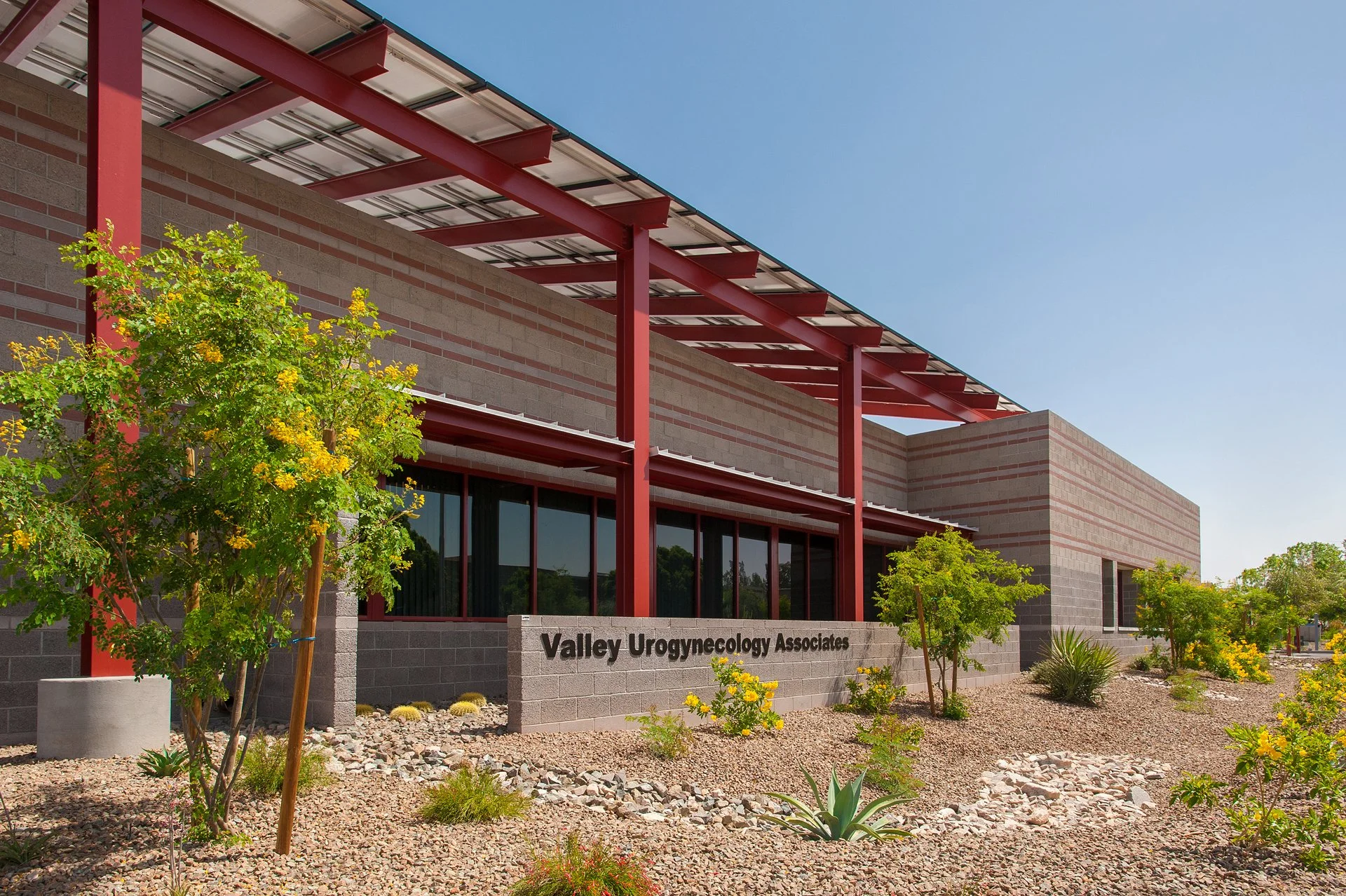 Medical office building, featuring modern architecture with red beams and desert landscaping.