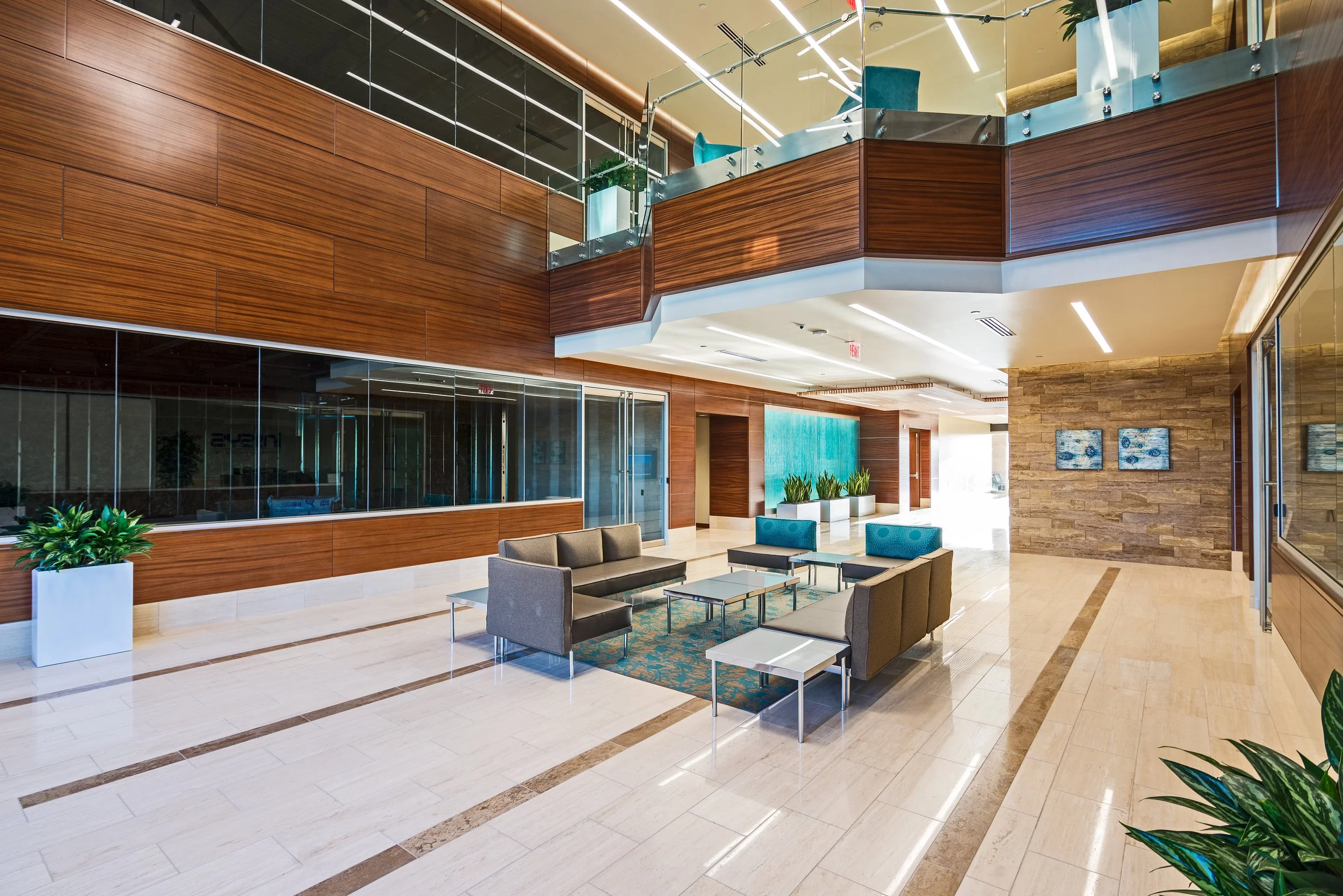 Modern office lobby interior with glass walls, wood paneling, and seating area at Chandler 202.