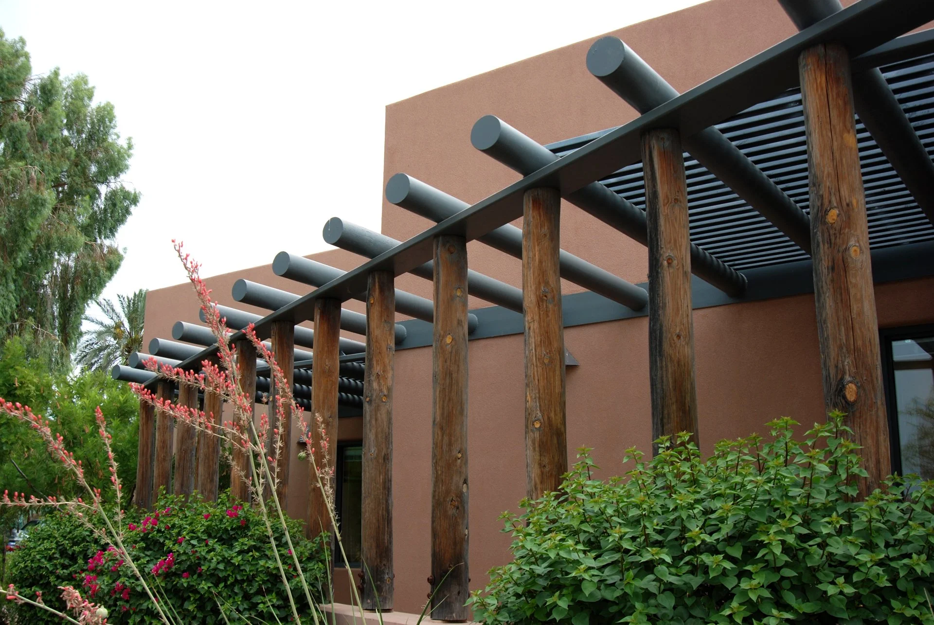 Adobe-style building with wooden pergola and desert plants