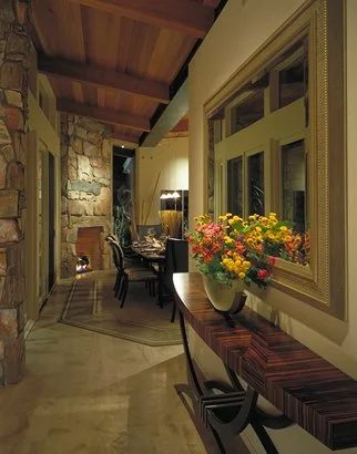 Modern hallway with wooden ceiling, stone accent wall, and decorated table. Includes flowers in a vase and dining area visible in the background.
