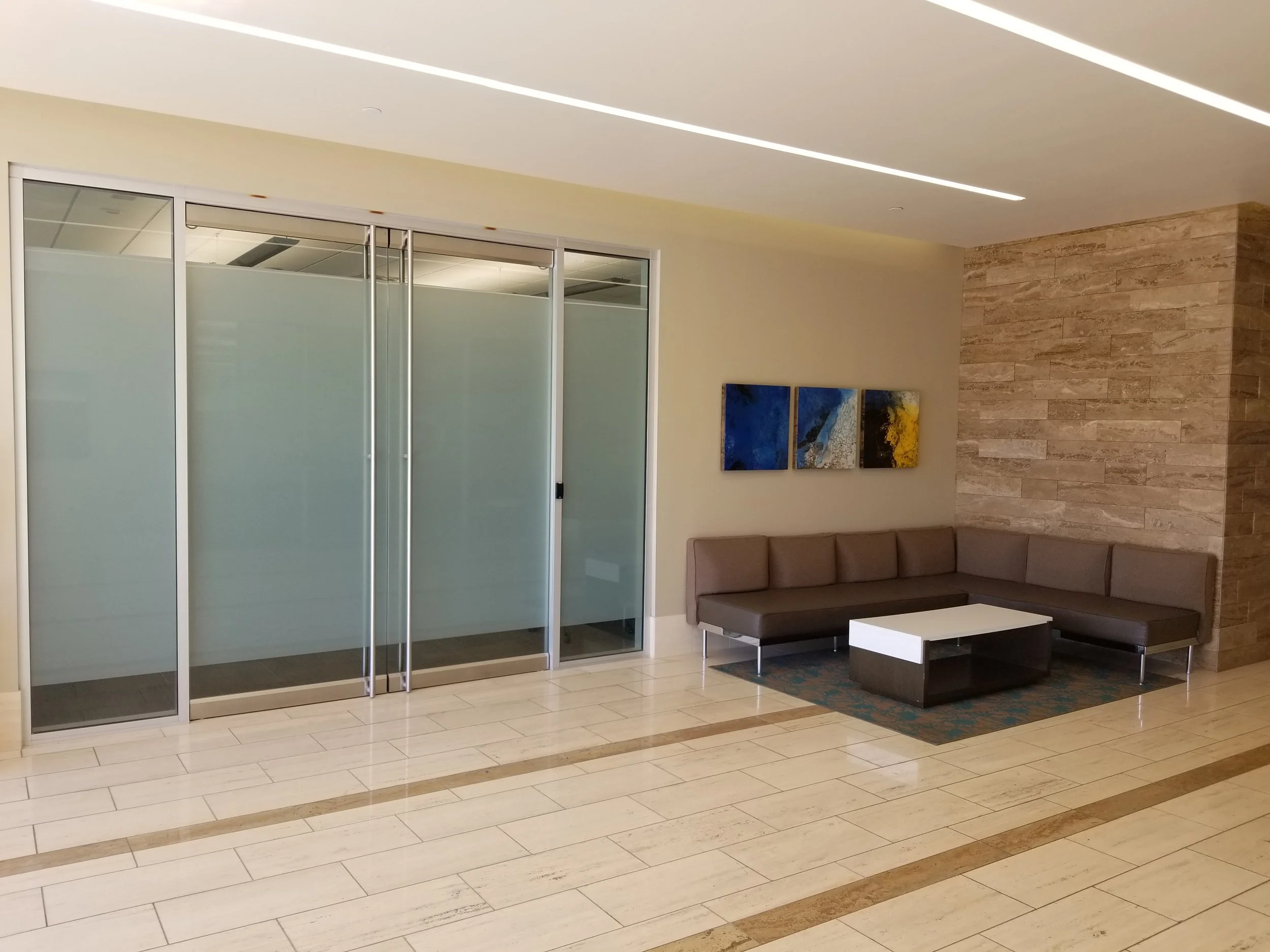 Modern lobby with seating area, frosted glass doors, and tiled flooring at Chandler 202.