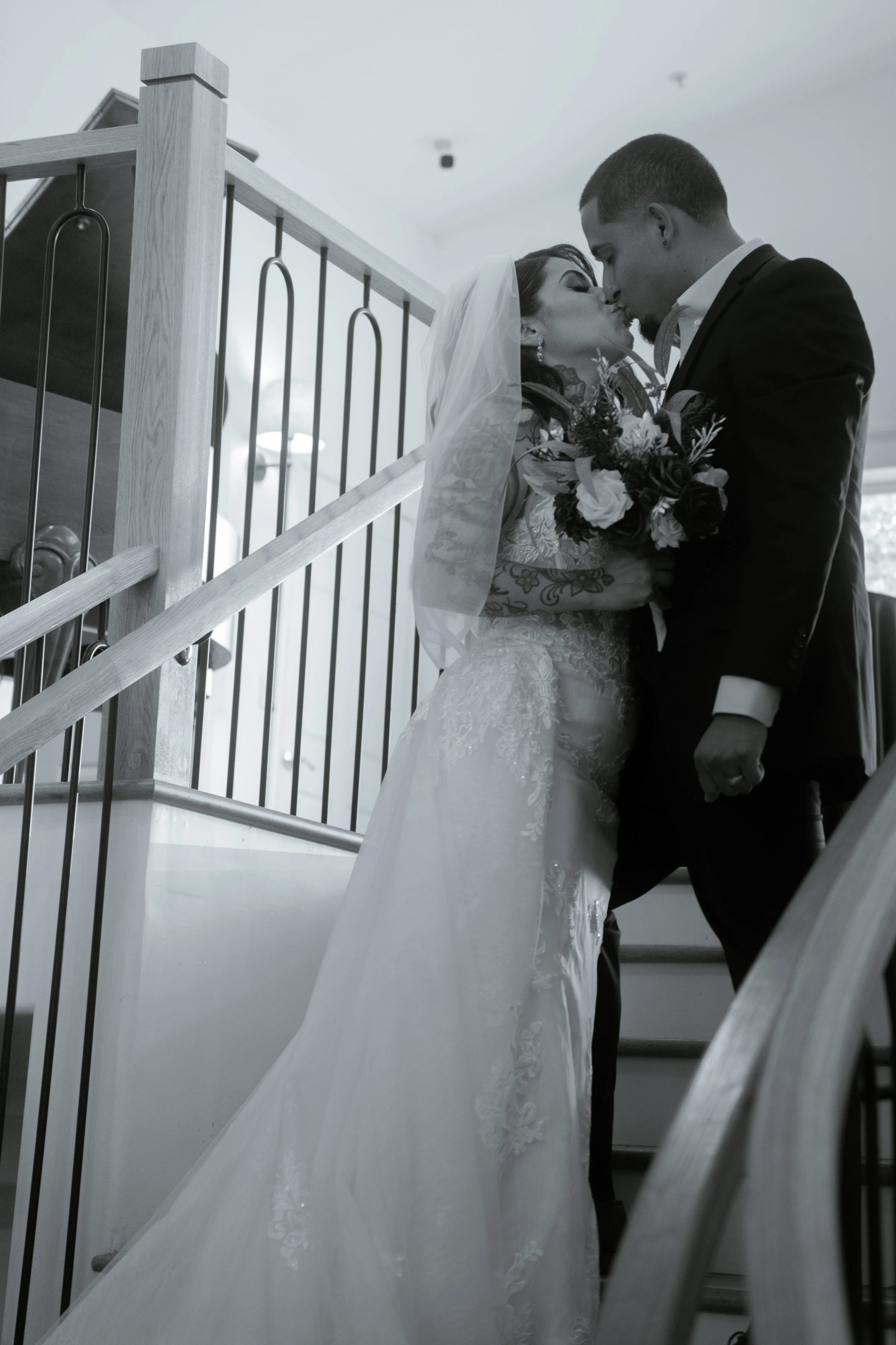 A bride and groom sharing a kiss on a staircase during their wedding.