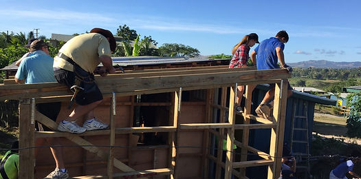 People working on a wooden house construction, installing the roof in a rural area.