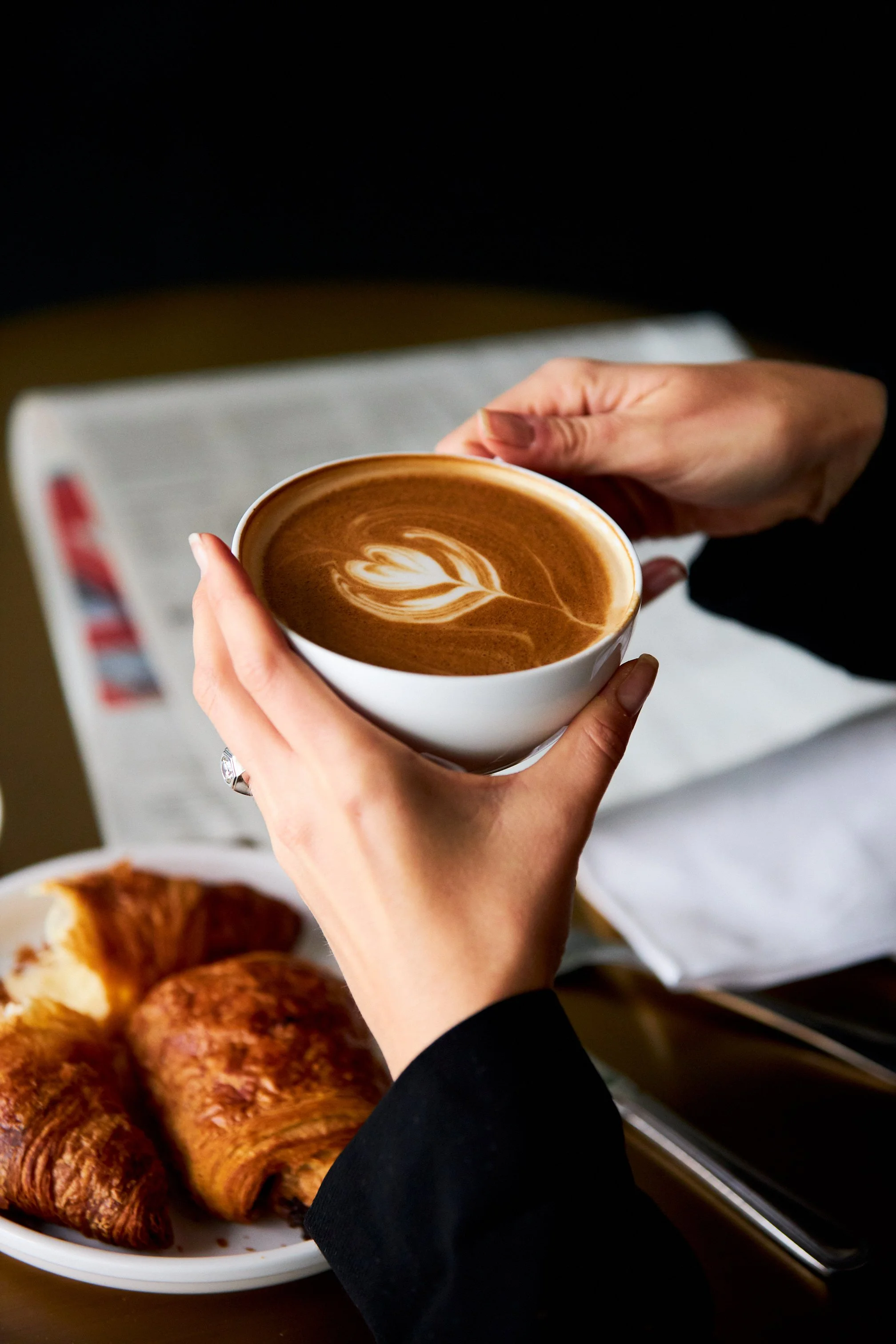 Photo of woman holding café latte with croissants at zinqué, a French restaurant