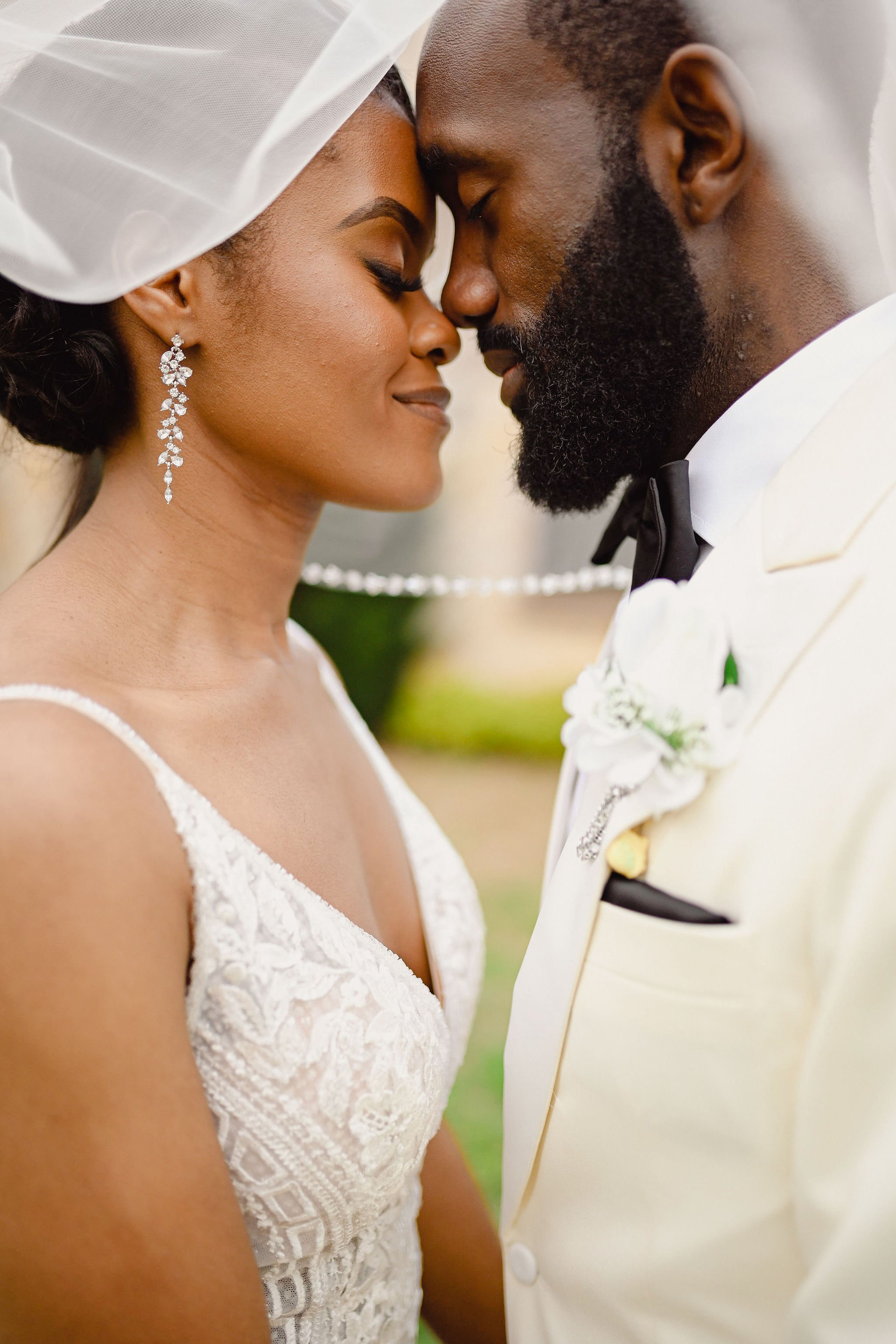 A close-up of a bride and groom with foreheads touching, eyes closed, during their wedding, both smiling gently.