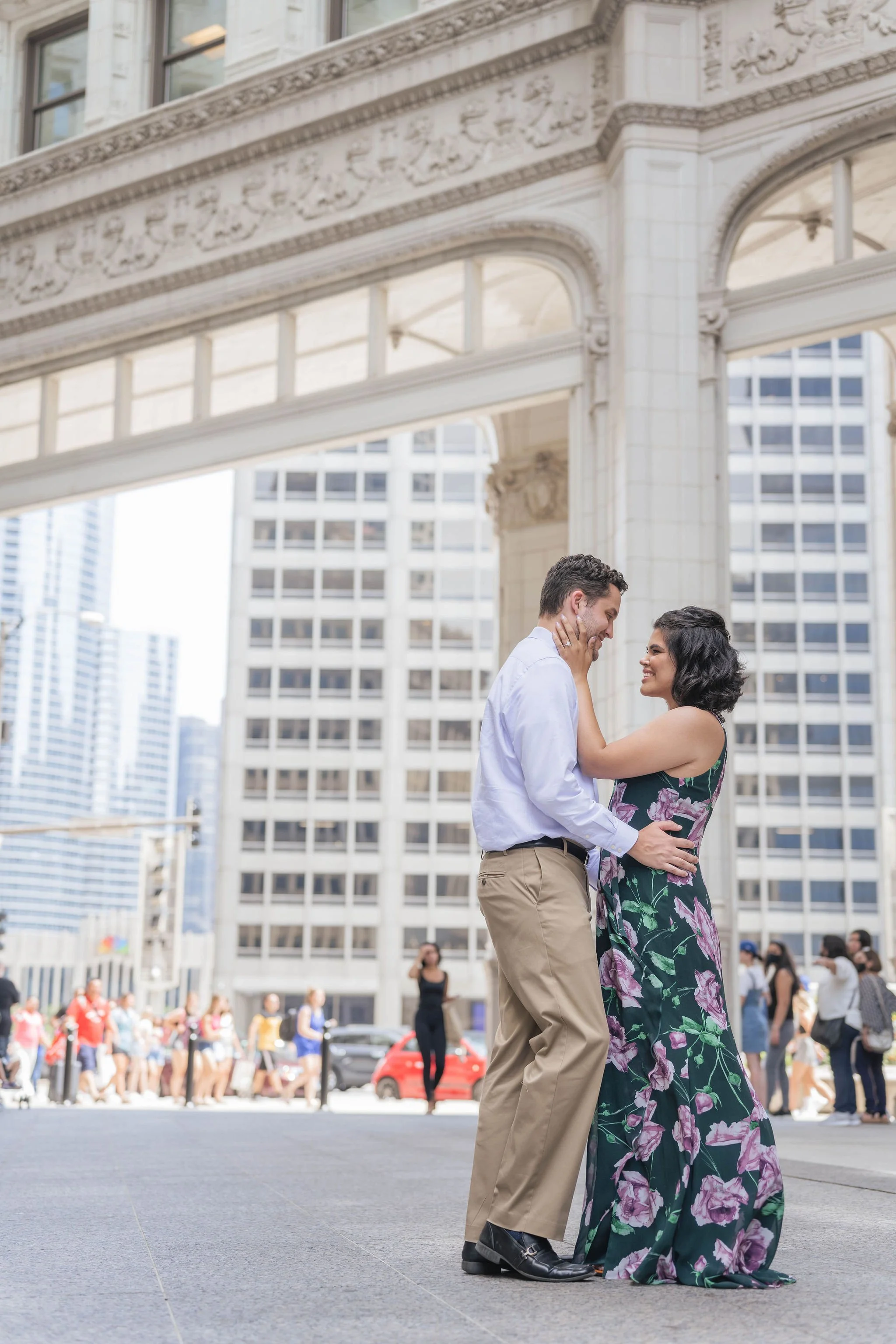 A couple dancing on a city street with tall buildings in the background, surrounded by onlookers.