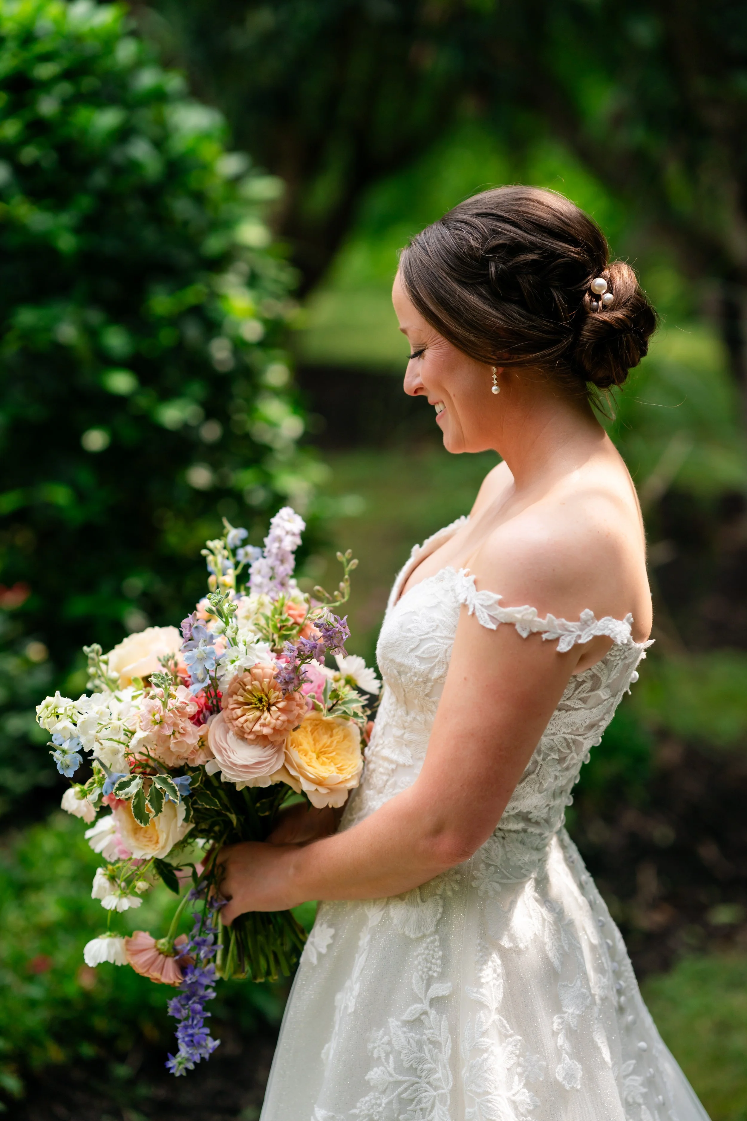 a bride is looking at her flowers while being surrounded by lush greenery
