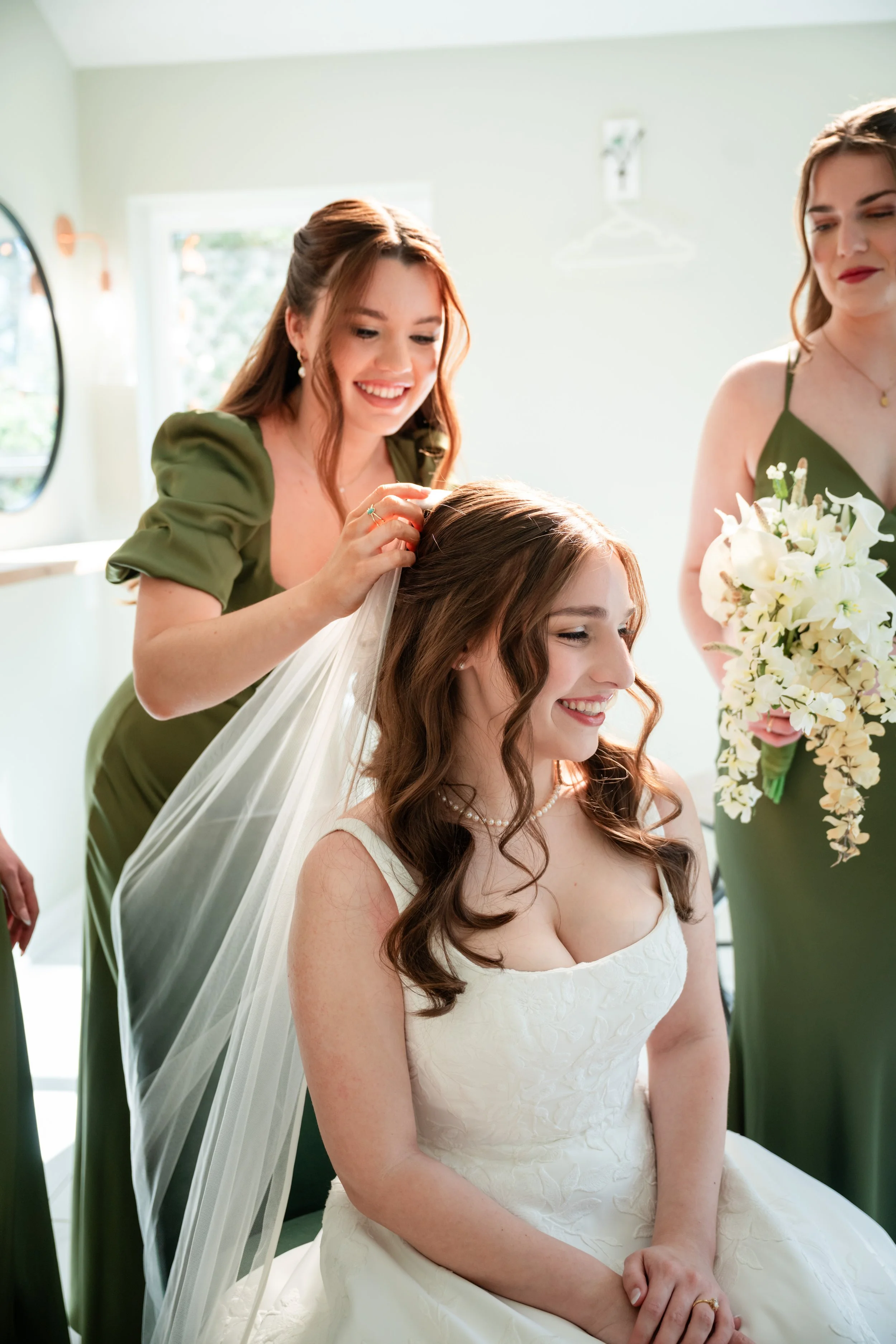 a bridesmaid is helping the bride with her veil 