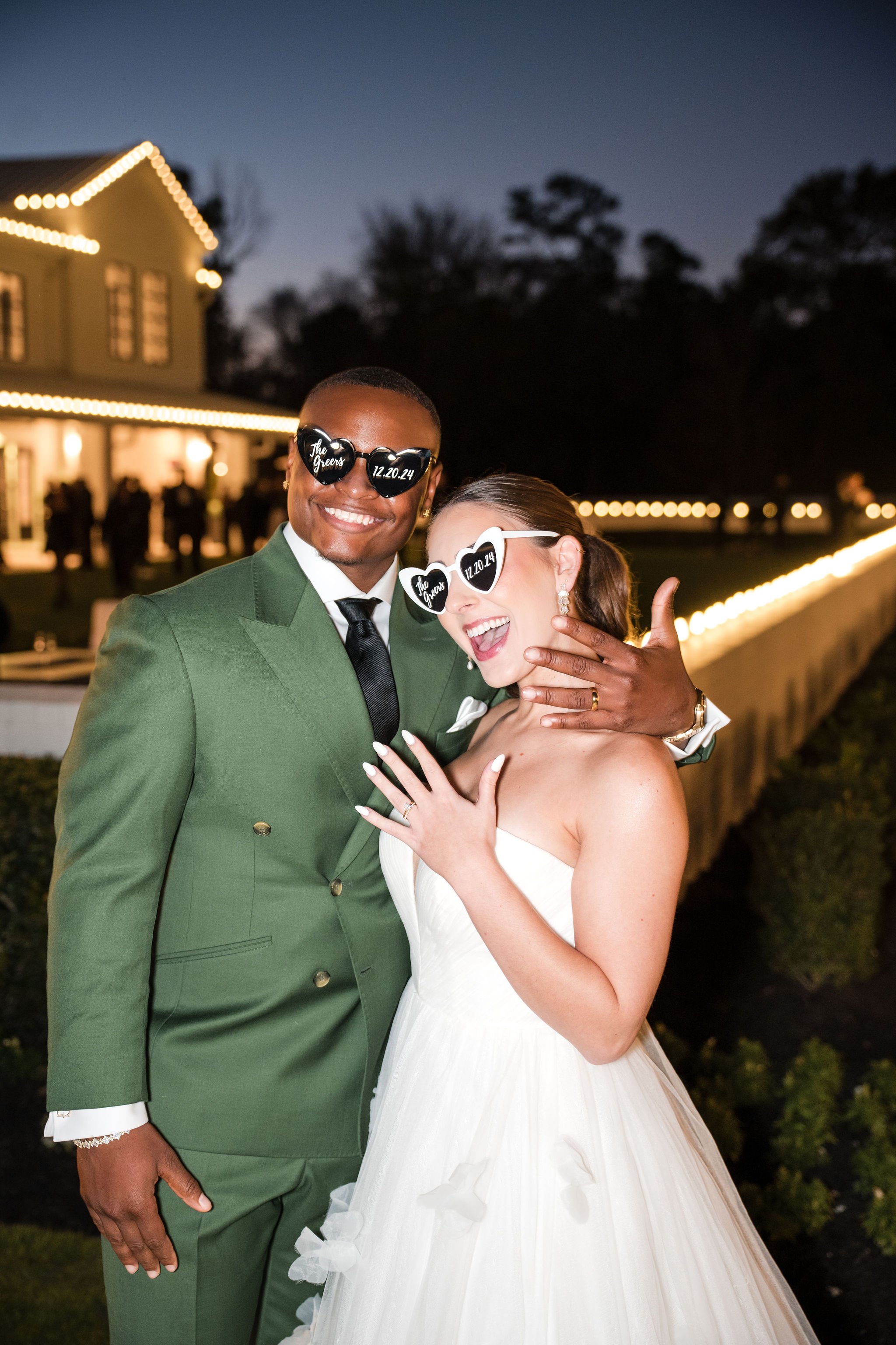 Happy bride and groom wearing sunglasses with wedding date and venue name, celebrating outdoors at night.