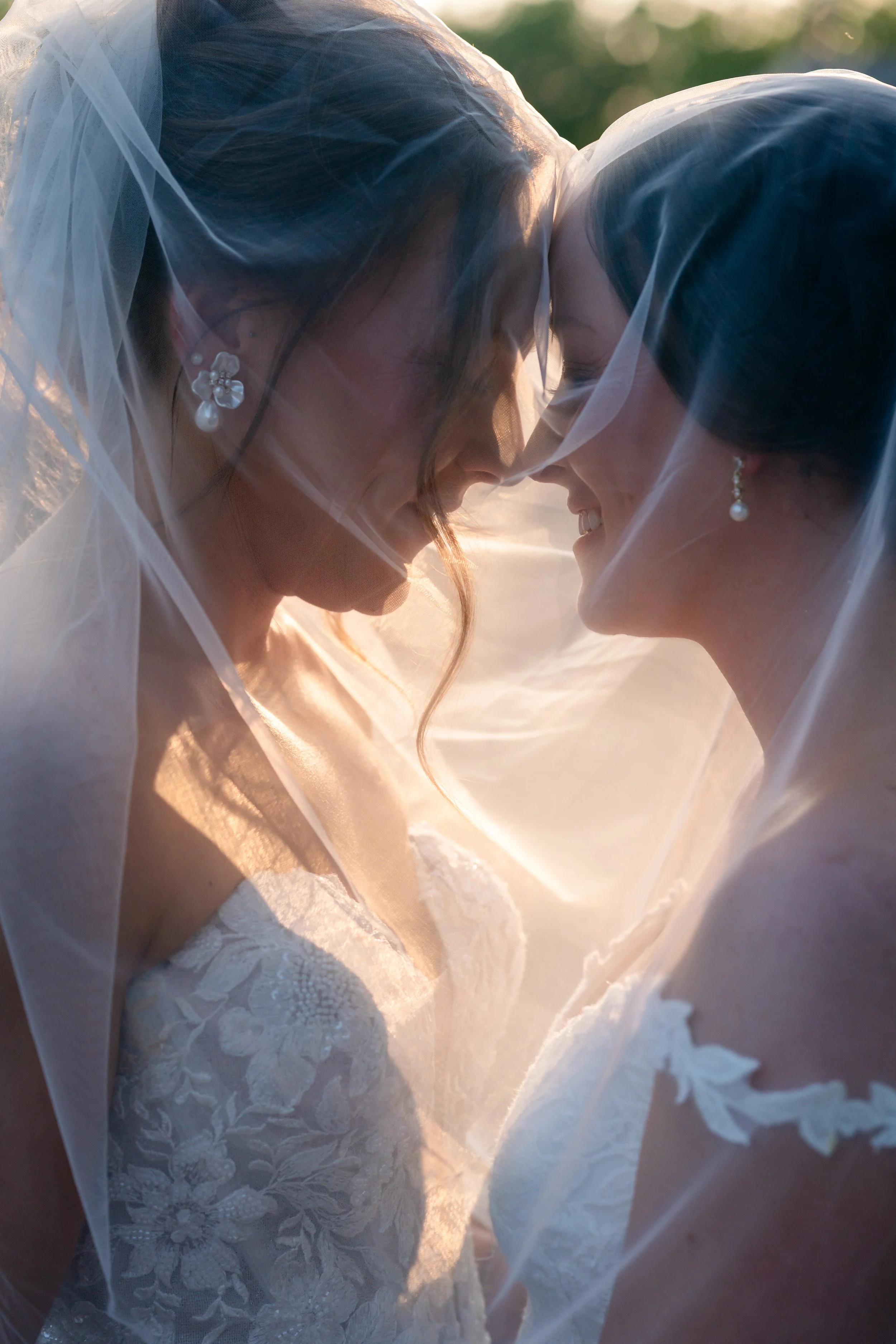 2 brides are looking at each other while taking sunset pictures 