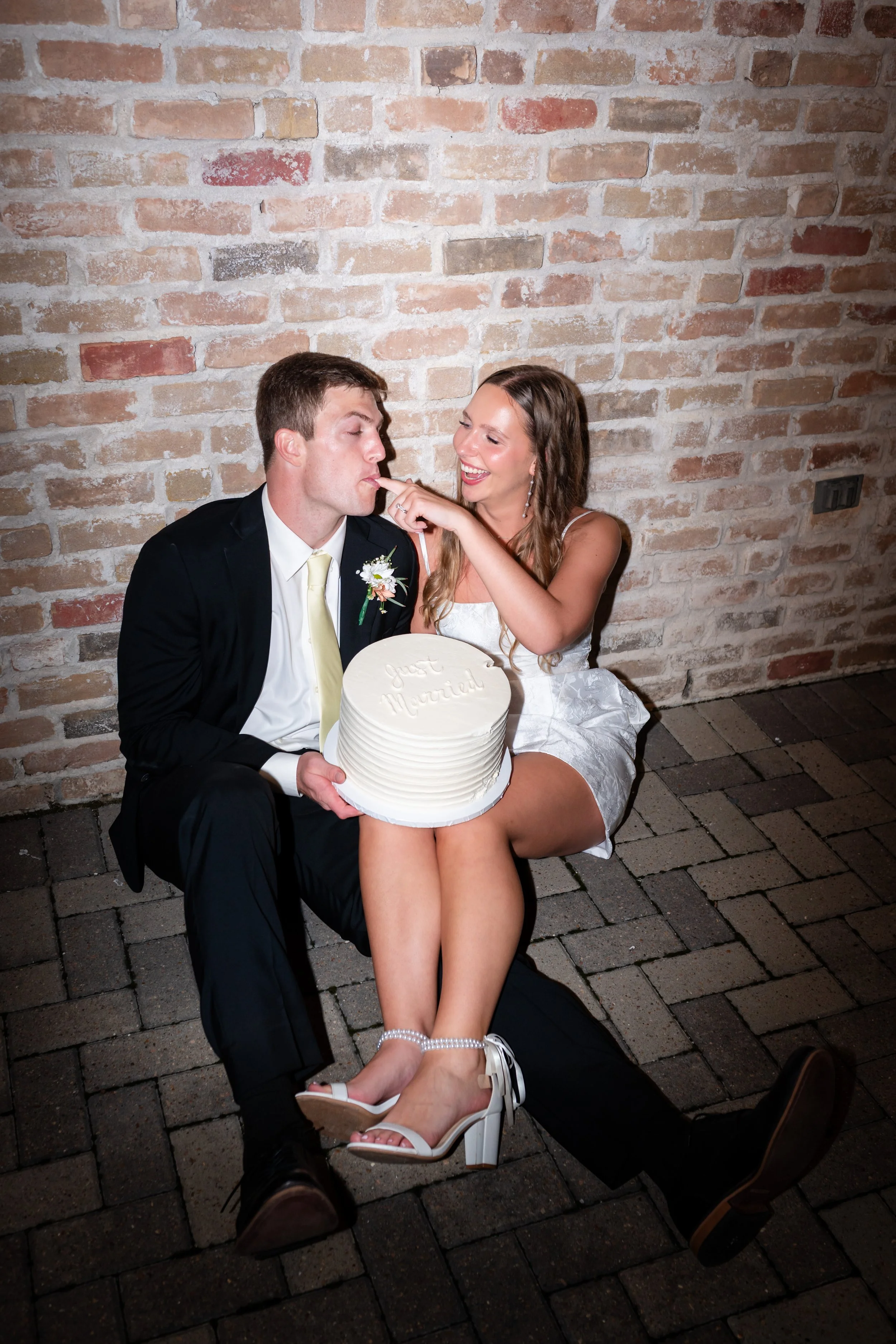 a couple is taking pictures with their cake outside