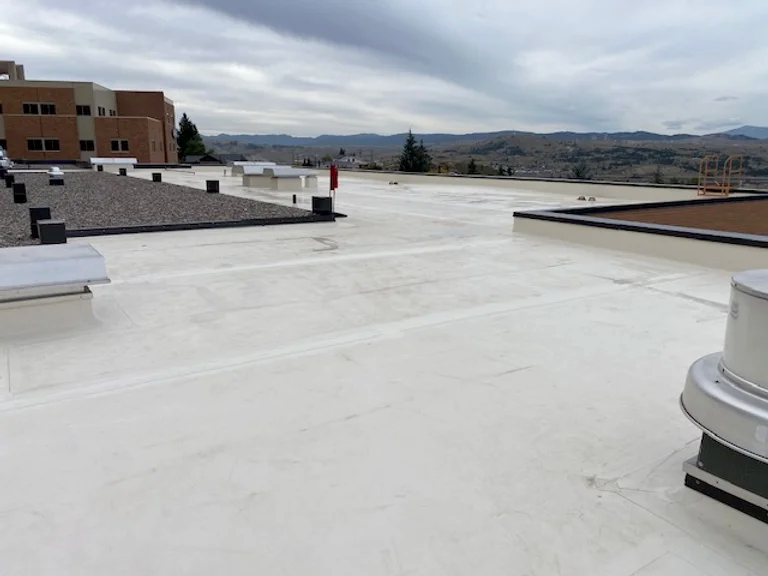 Flat rooftop with ventilation systems and building in the background