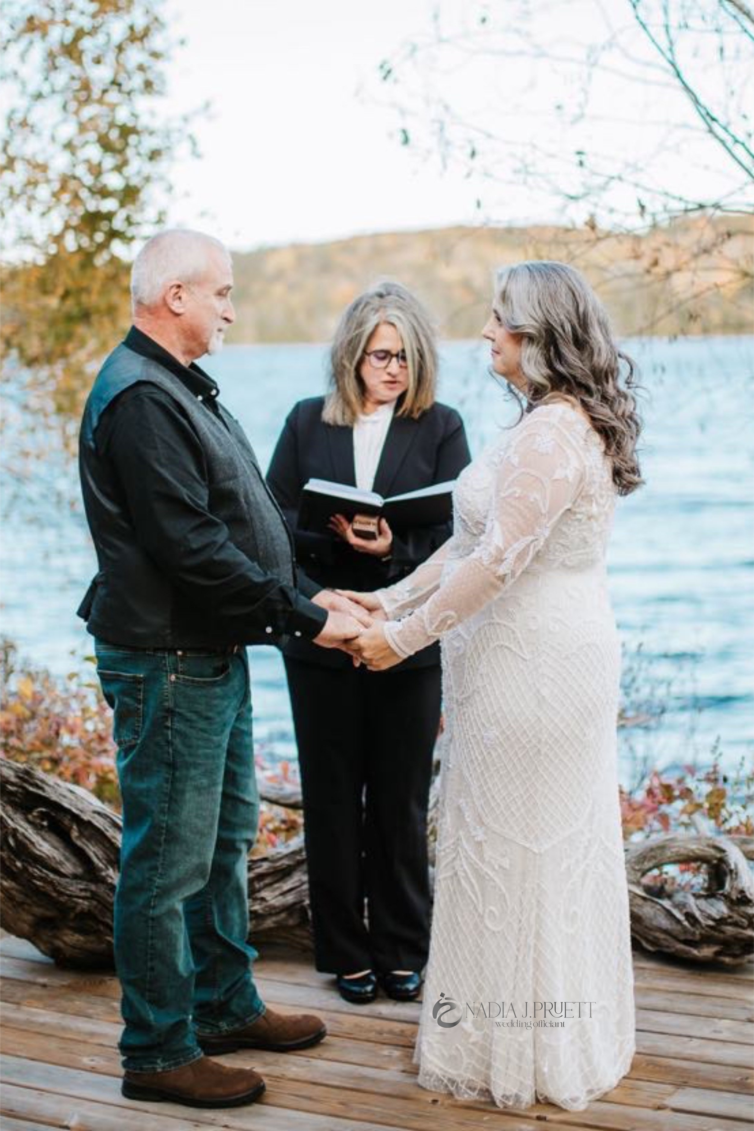 Nadia Pruett Officiant with an older bride and groom standing on a wooden dock by a lake performing a ceremony