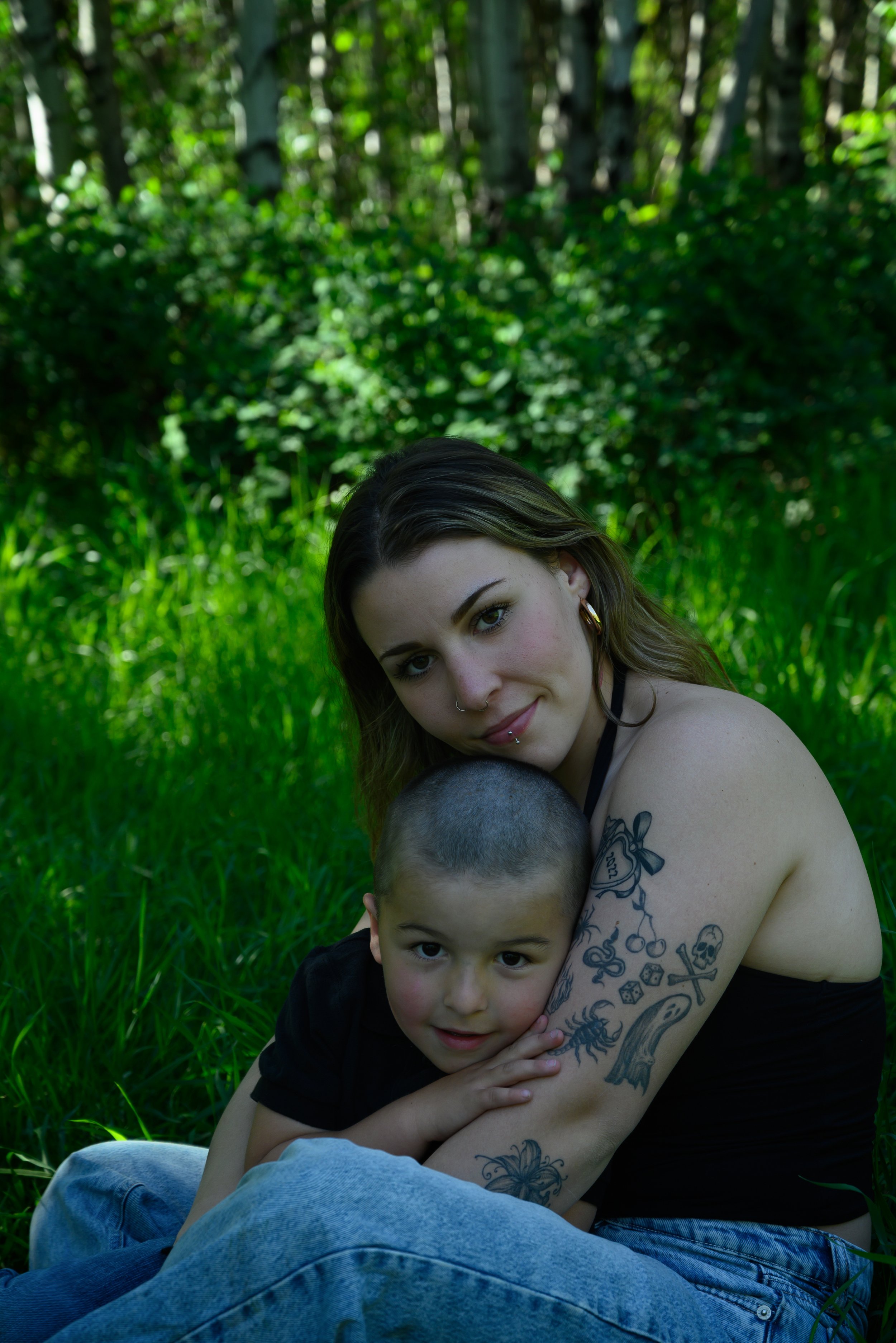 Mother and son photo taken in St. Albert. They are seated in a grassy area the young child seated in his mothers lap.