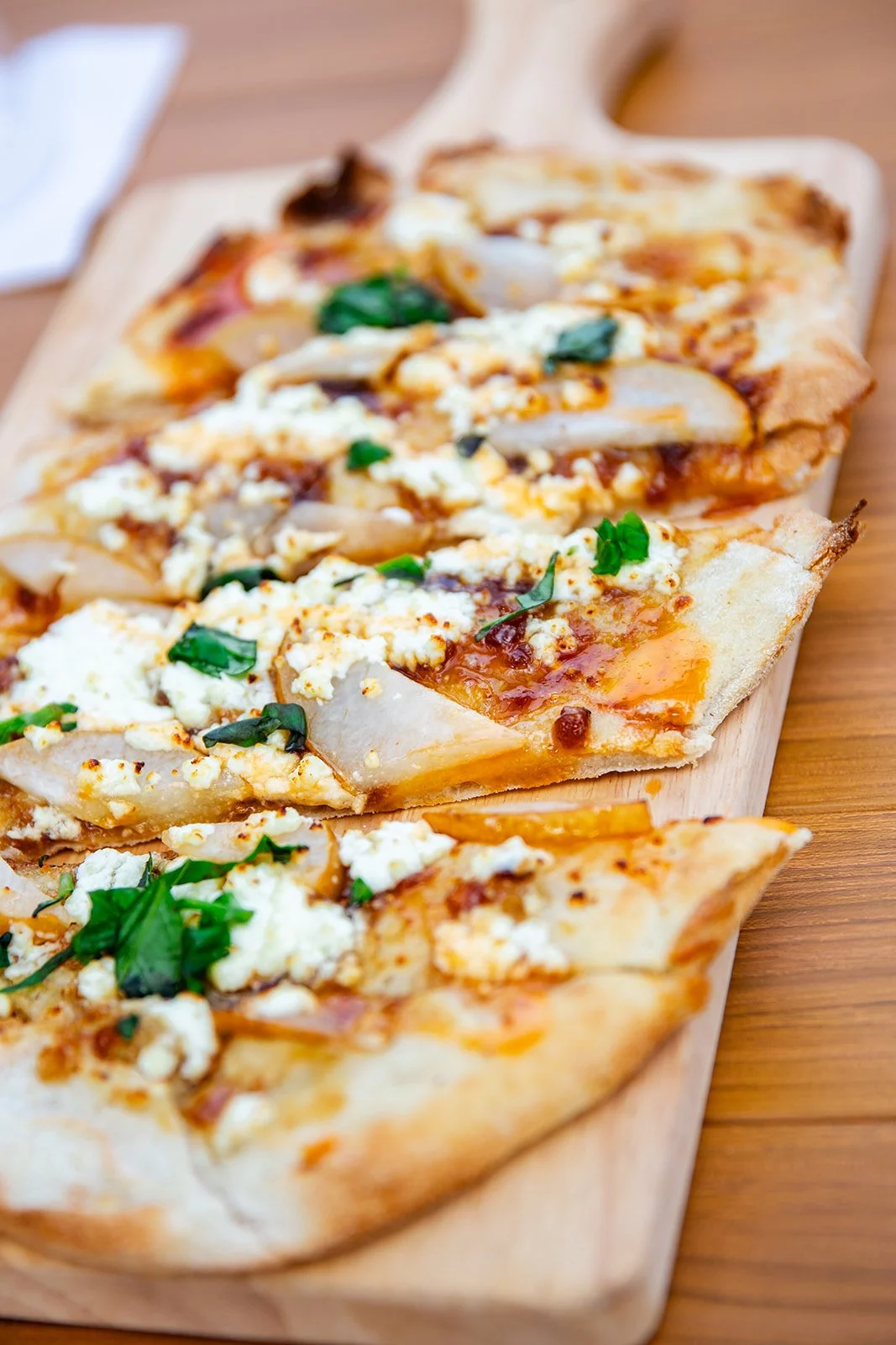 Flatbread with arugula, prosciutto, and figs on a wooden serving board.