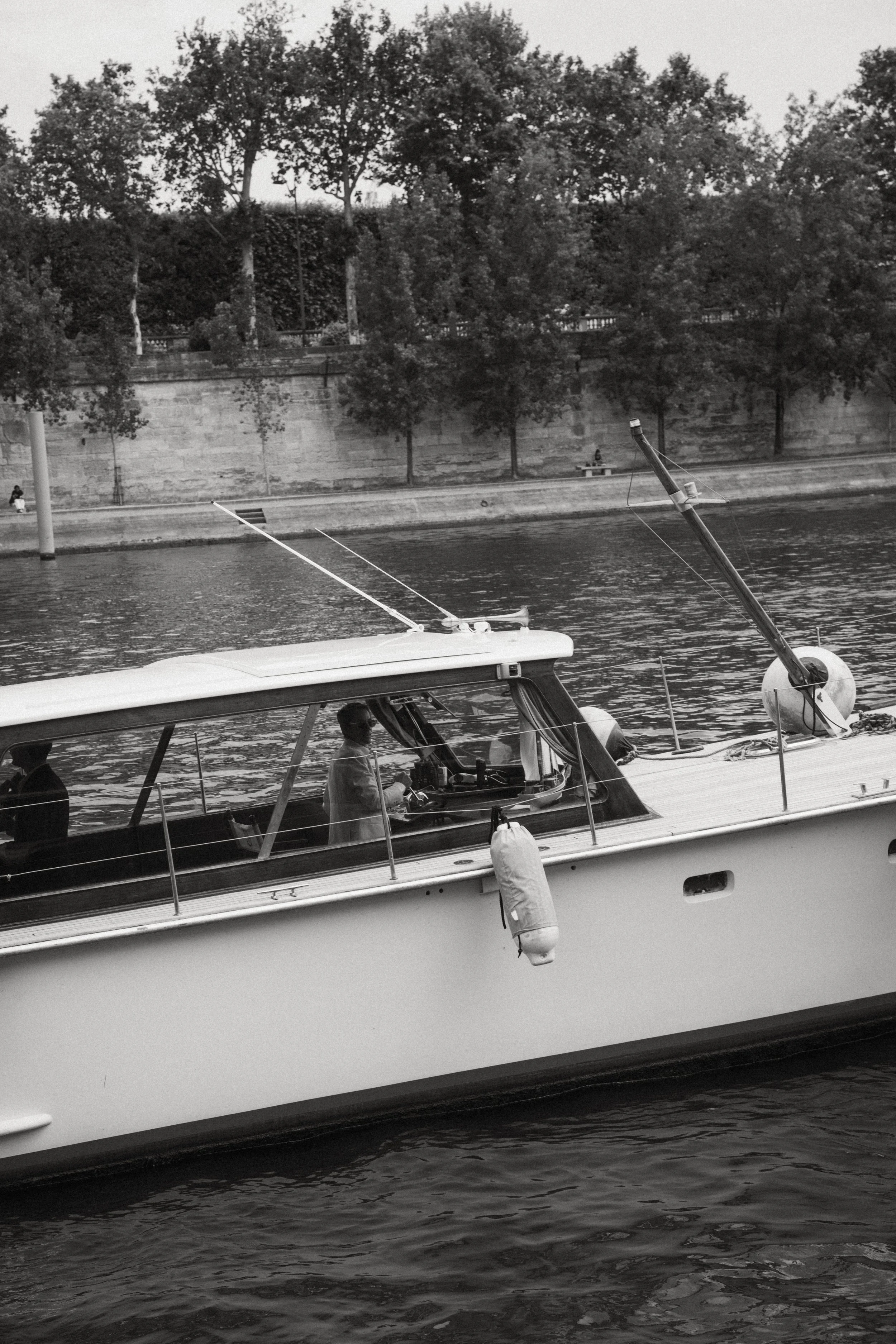 Bateau à moteur sur une rivière avec vue sur un mur en pierre et des arbres en arrière-plan.