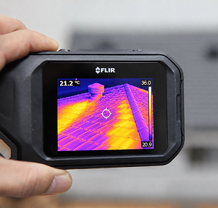 Thermal camera view of a rooftop with heat variation, showing cold areas in blue and warm areas in yellow and purple.