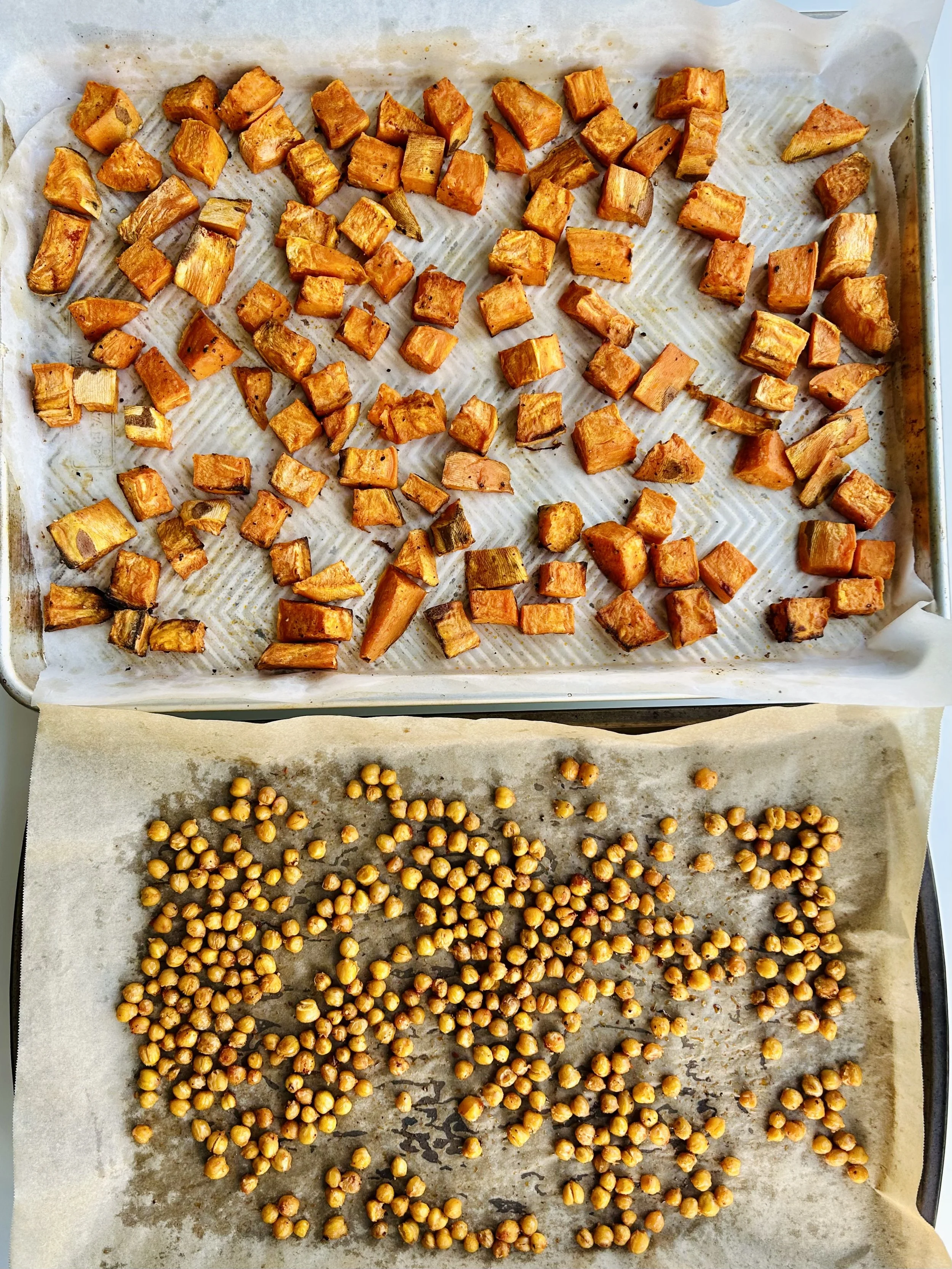 Roasted yam cubes and crispy chickpeas on a baking sheet, fresh from the oven for a Caesar salad.