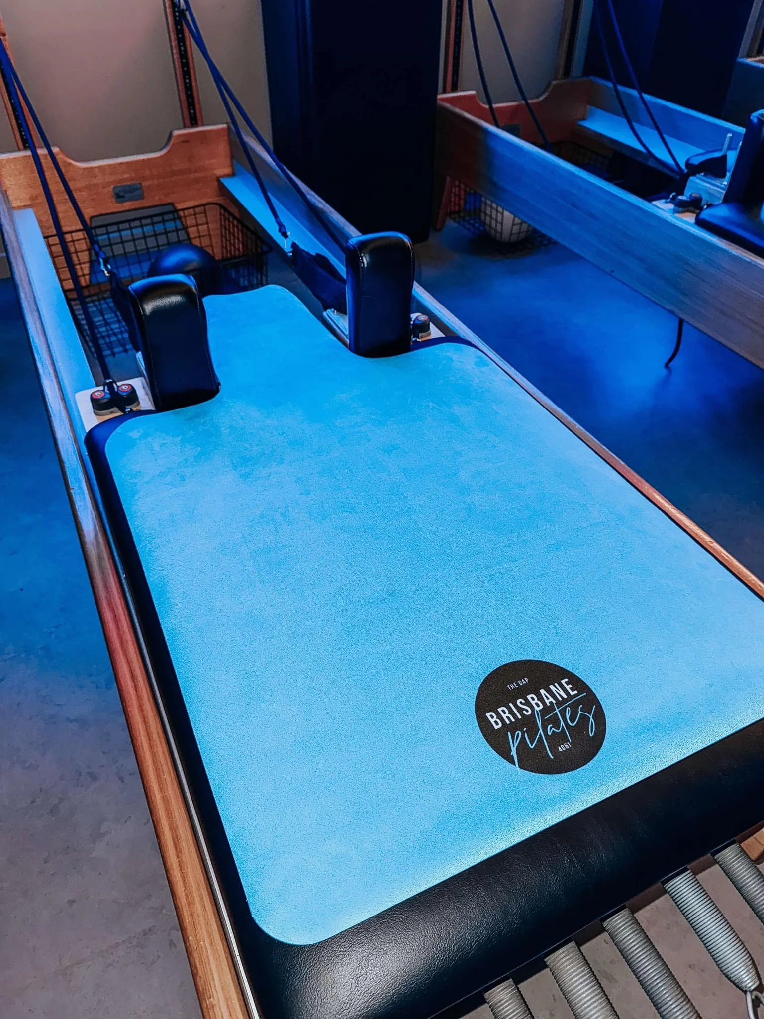 An air hockey table with a blue playing surface, black paddles, and a black puck, located in a gaming area with other arcade games.