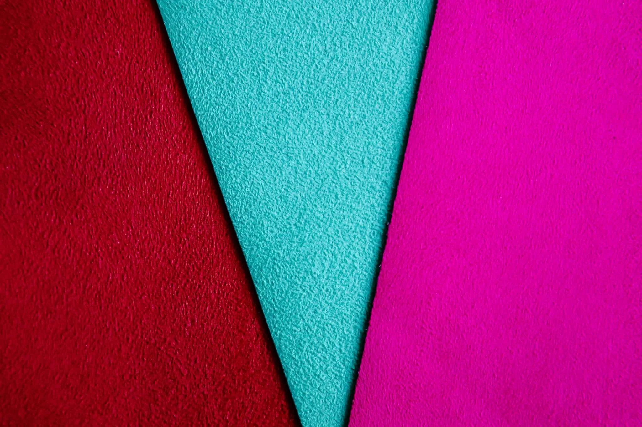 Close-up of three textured colorful foam sheets in red, teal, and pink arranged in a V-shape.