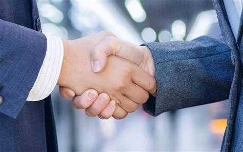 Close-up on the hands of two people shaking hands, wearing business suits.